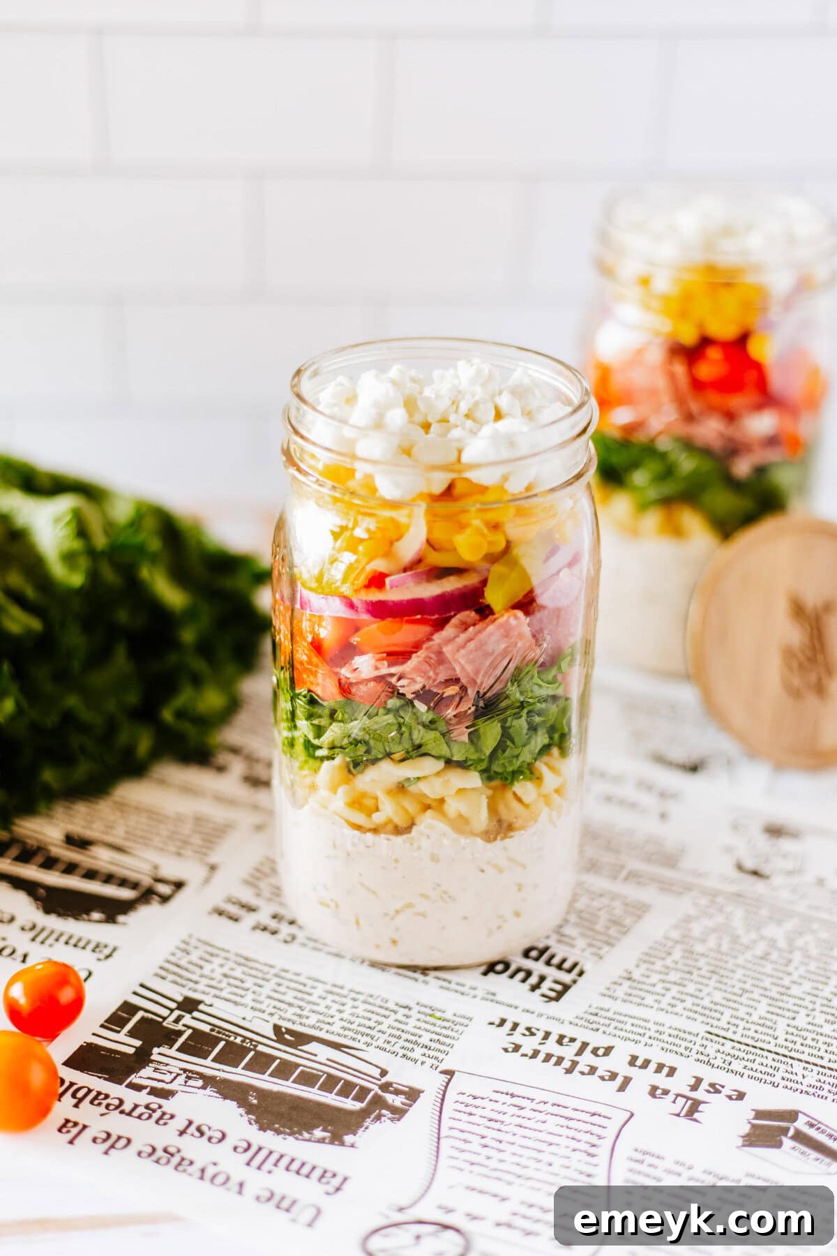 Two Italian Pasta Mason Jar Salads in jars, ready to be stored, with a focus on their appealing and well-layered appearance.