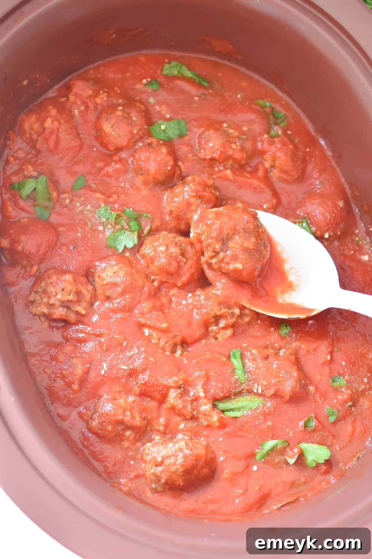 Rice Spiked Meatballs 3 Porcupine Meatballs simmering in a slow cooker, rich with tomato sauce.