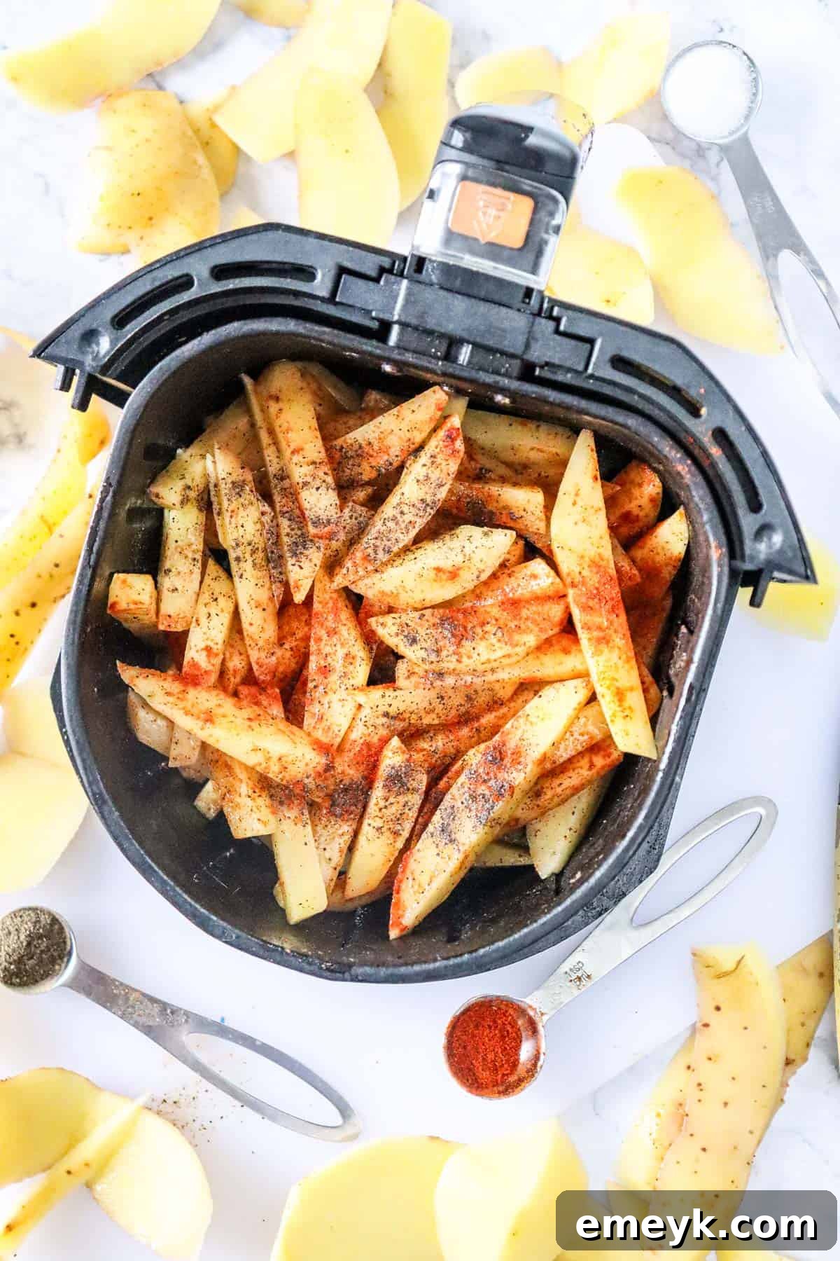 Seasoned potato fries arranged in a single layer in an air fryer basket, ready for cooking