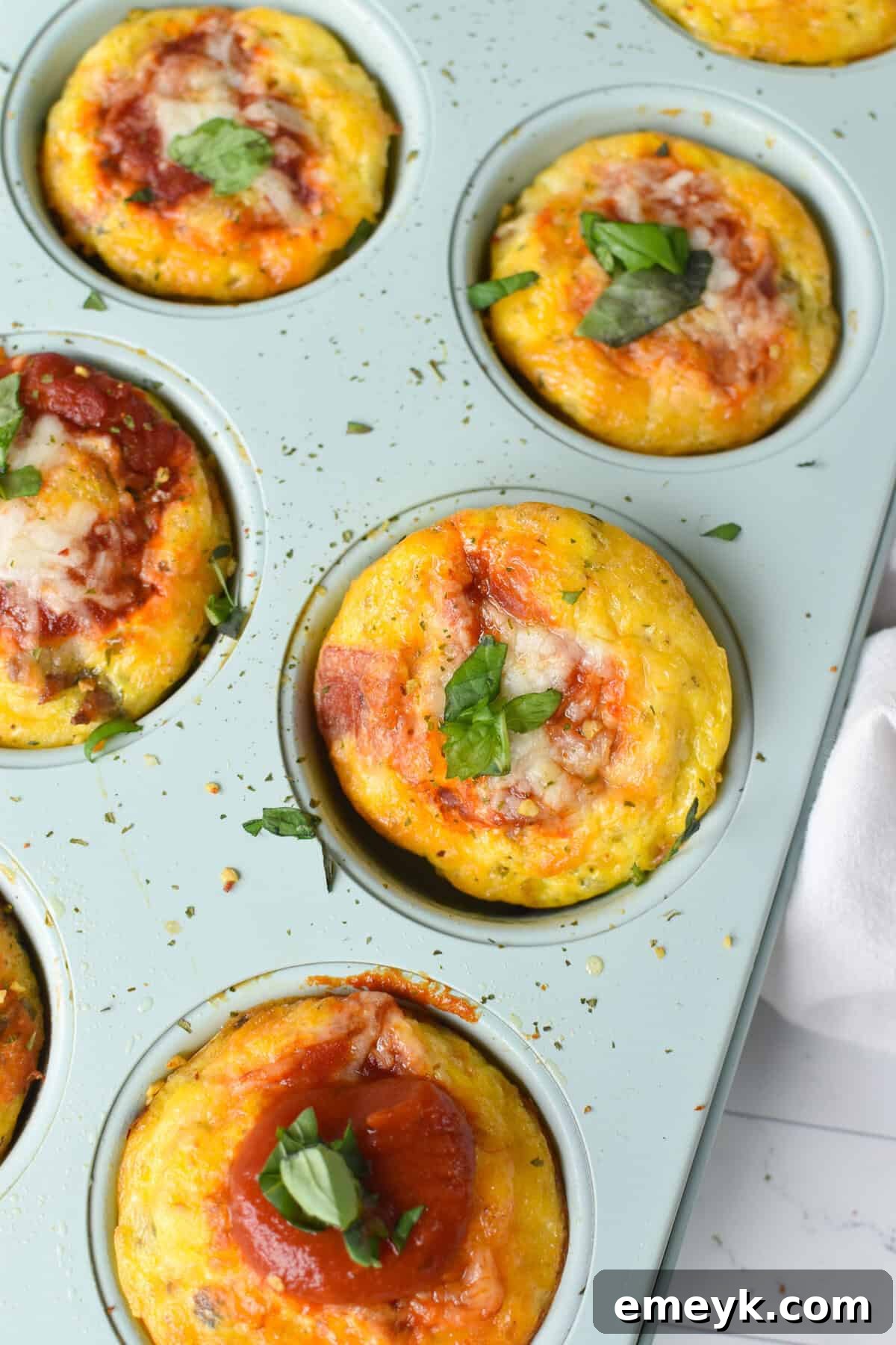 Freshly baked Pizza Egg Muffins cooling in a muffin tin, showcasing their golden-brown tops and colorful ingredients