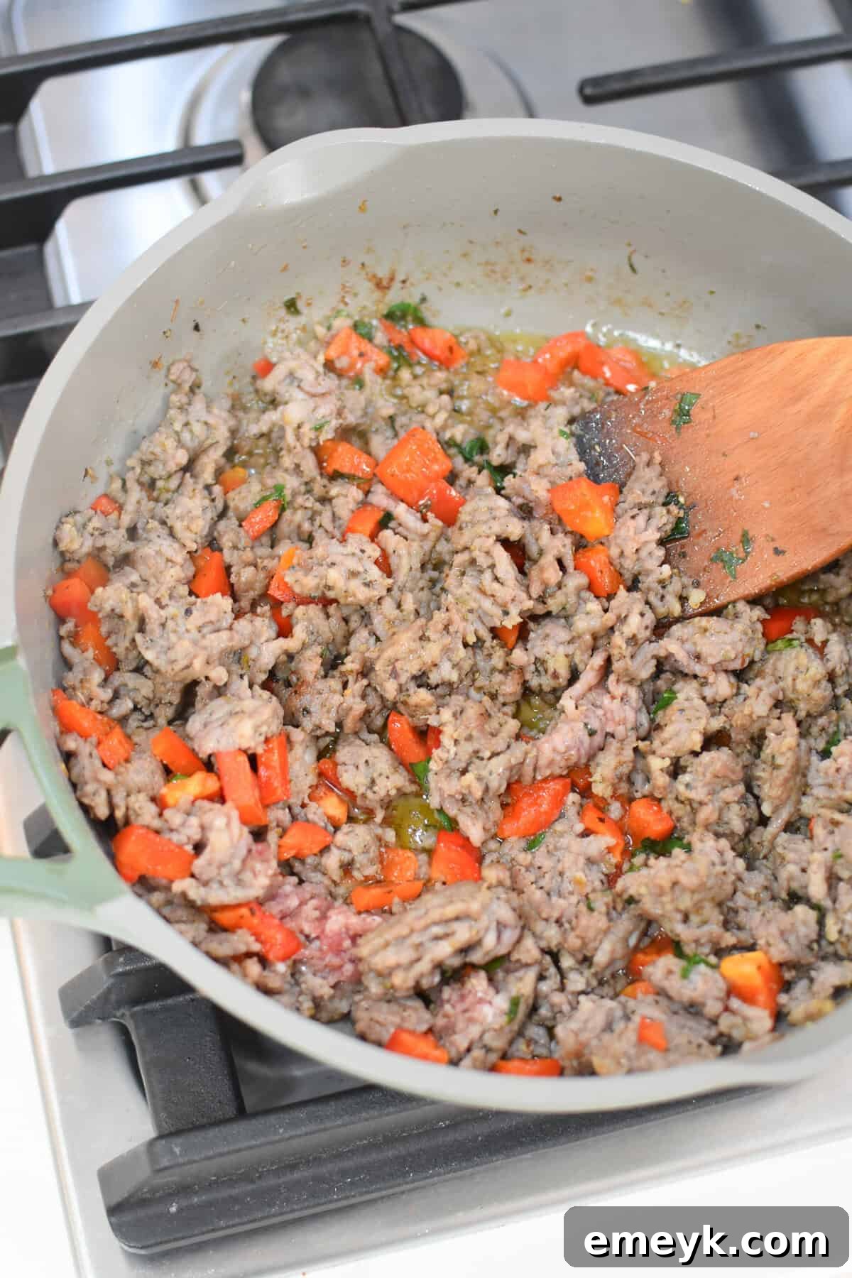 Ground turkey sausage cooking in a skillet with Italian seasoning, garlic powder, onion powder, and cayenne pepper