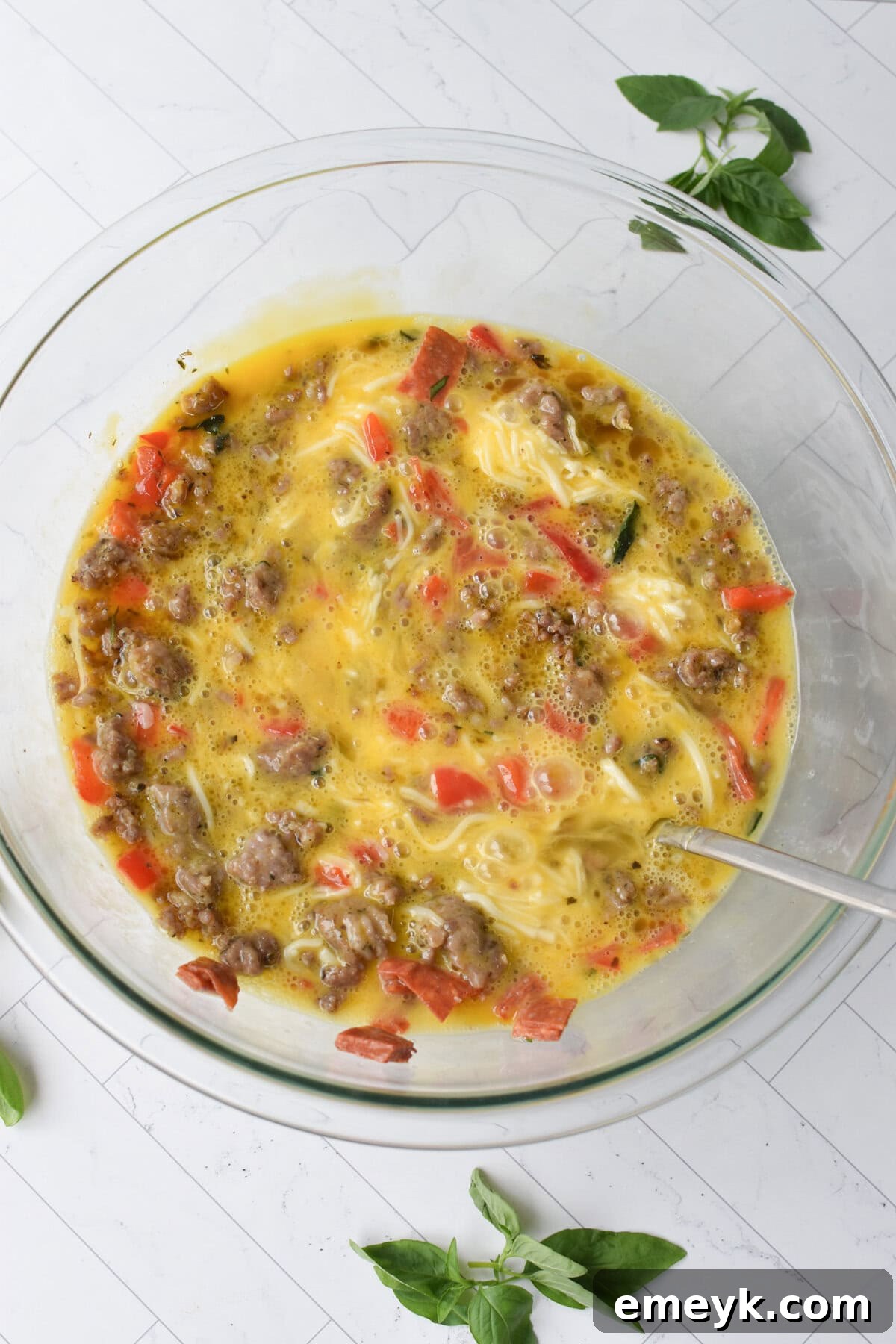 A large mixing bowl containing the combined sausage, bell pepper, pepperoni, and mozzarella cheese mixture