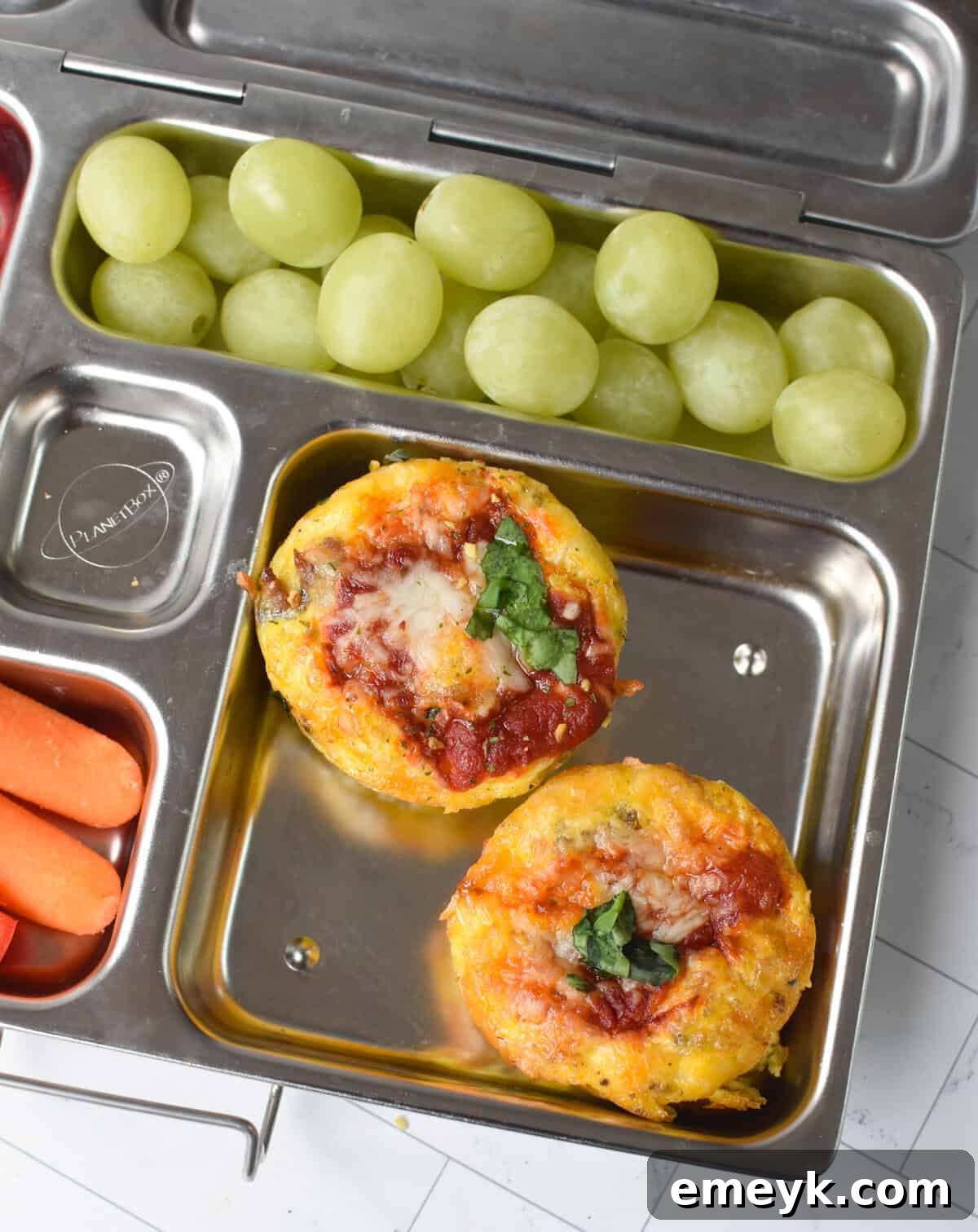 Pizza Egg Muffins neatly packed into a lunchbox alongside fresh fruit and vegetables for a healthy meal