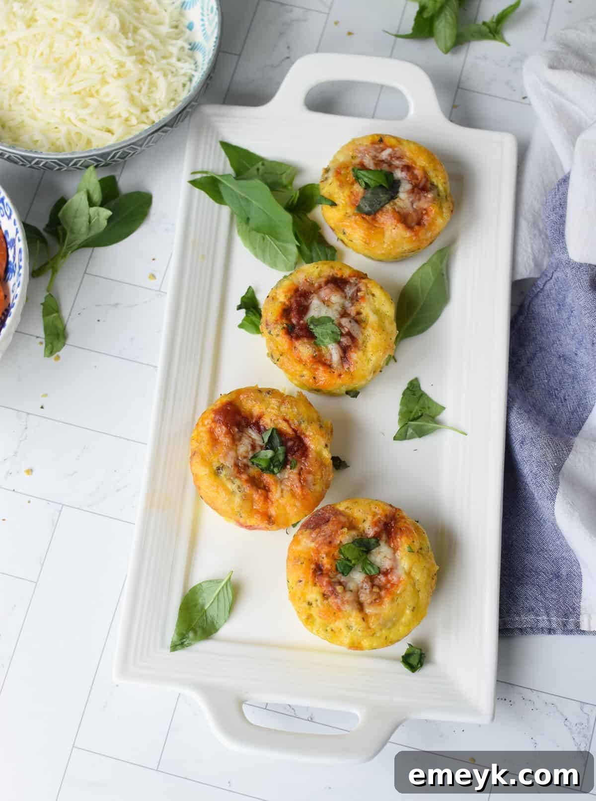 A close-up shot of a single Pizza Egg Muffin on a white plate, showcasing its fluffy texture and savory fillings
