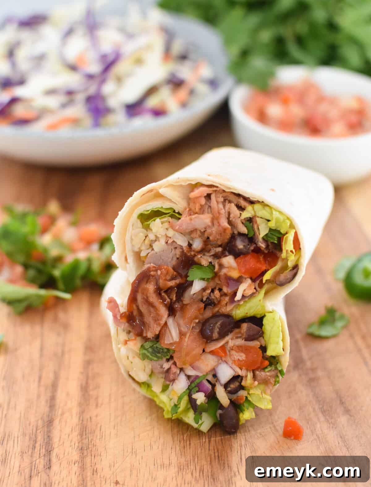 Smoked Pork Burrito Sensations 10 A perfectly sliced Pulled Pork Burrito, revealing its delicious layers of filling on a wooden cutting board