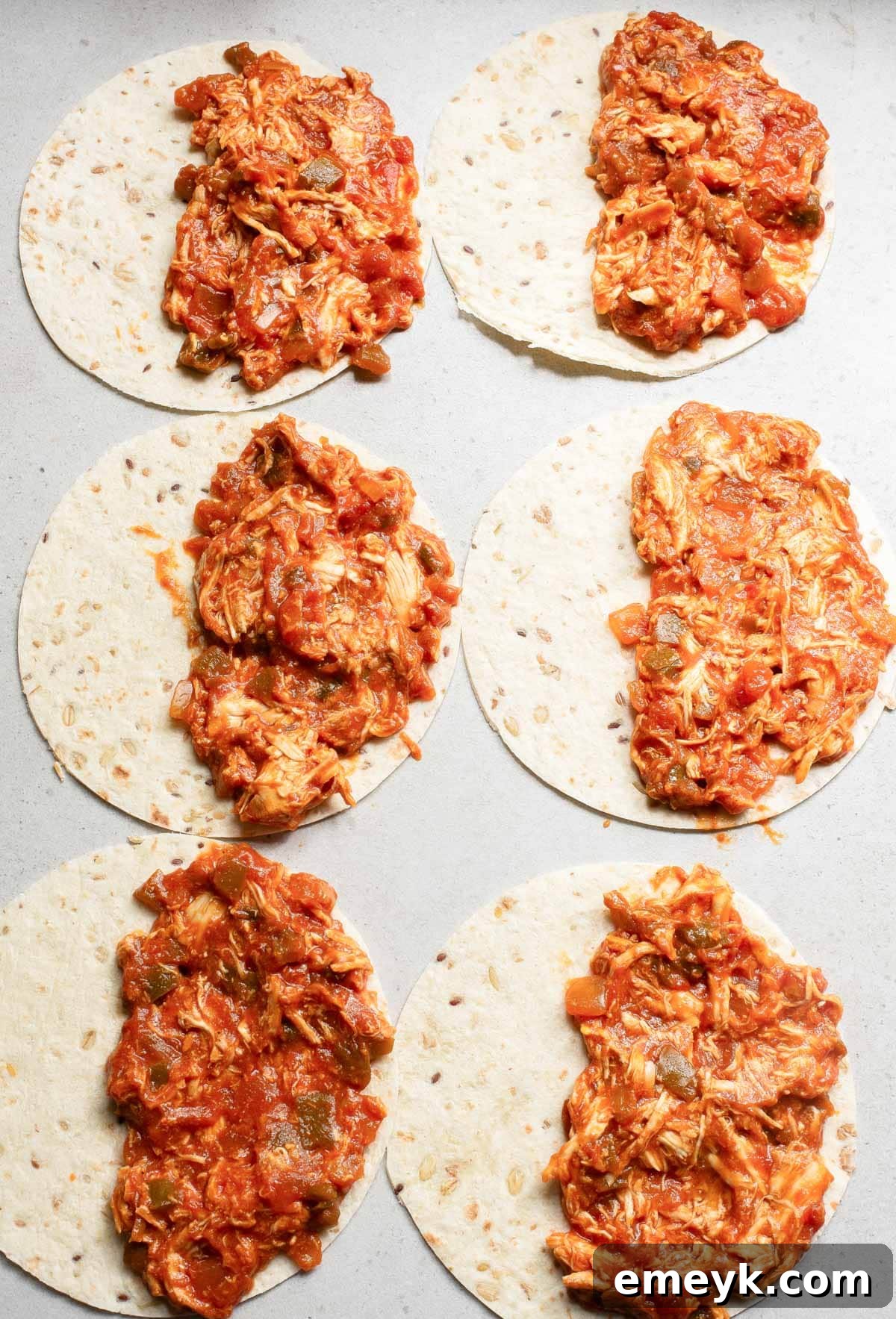 Chicken and cheese mixture spread on a tortilla, ready to be folded