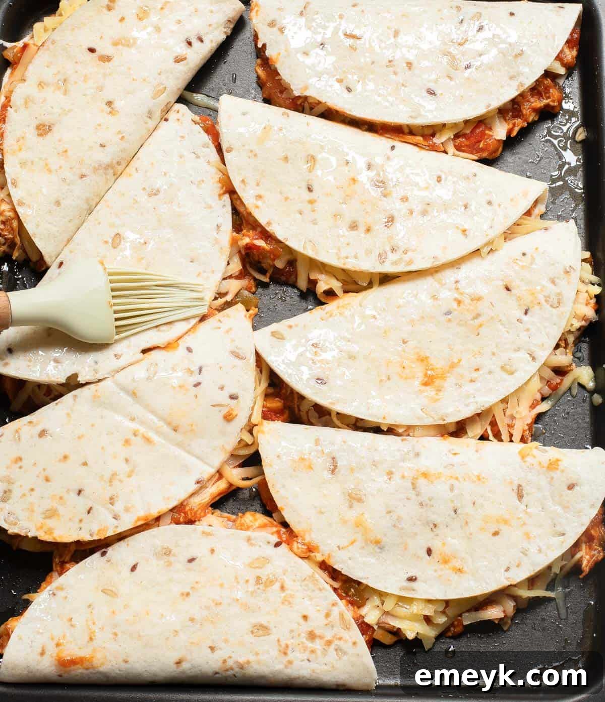Baked Chicken Tacos neatly arranged on a baking sheet before going into the oven