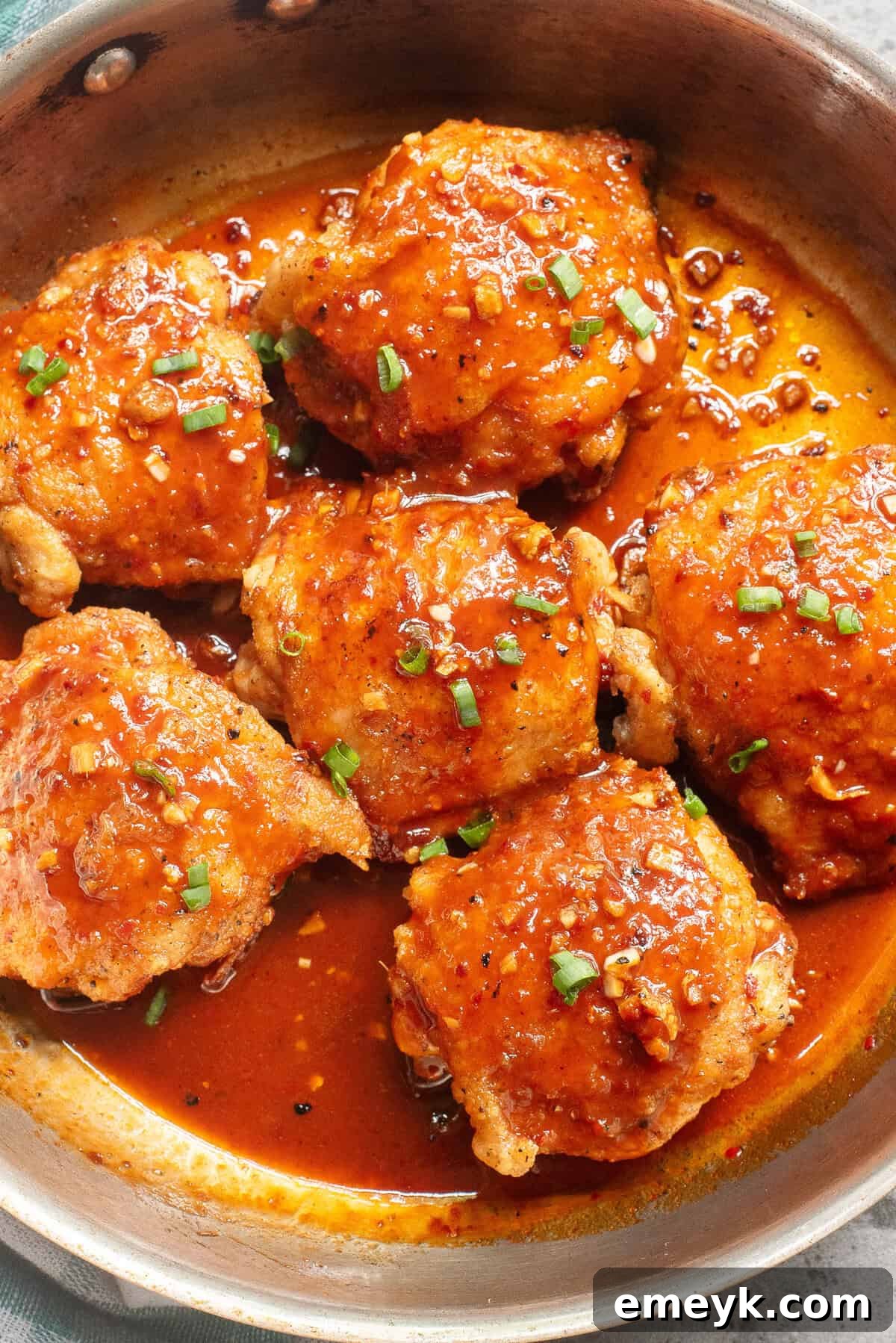 Glistening Honey Ginger Chicken thighs simmering in a skillet, ready to serve.