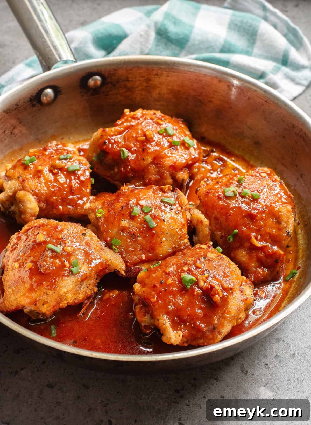 Honey Ginger Chicken simmering in a non-stick skillet, coated in a rich, glossy sauce.
