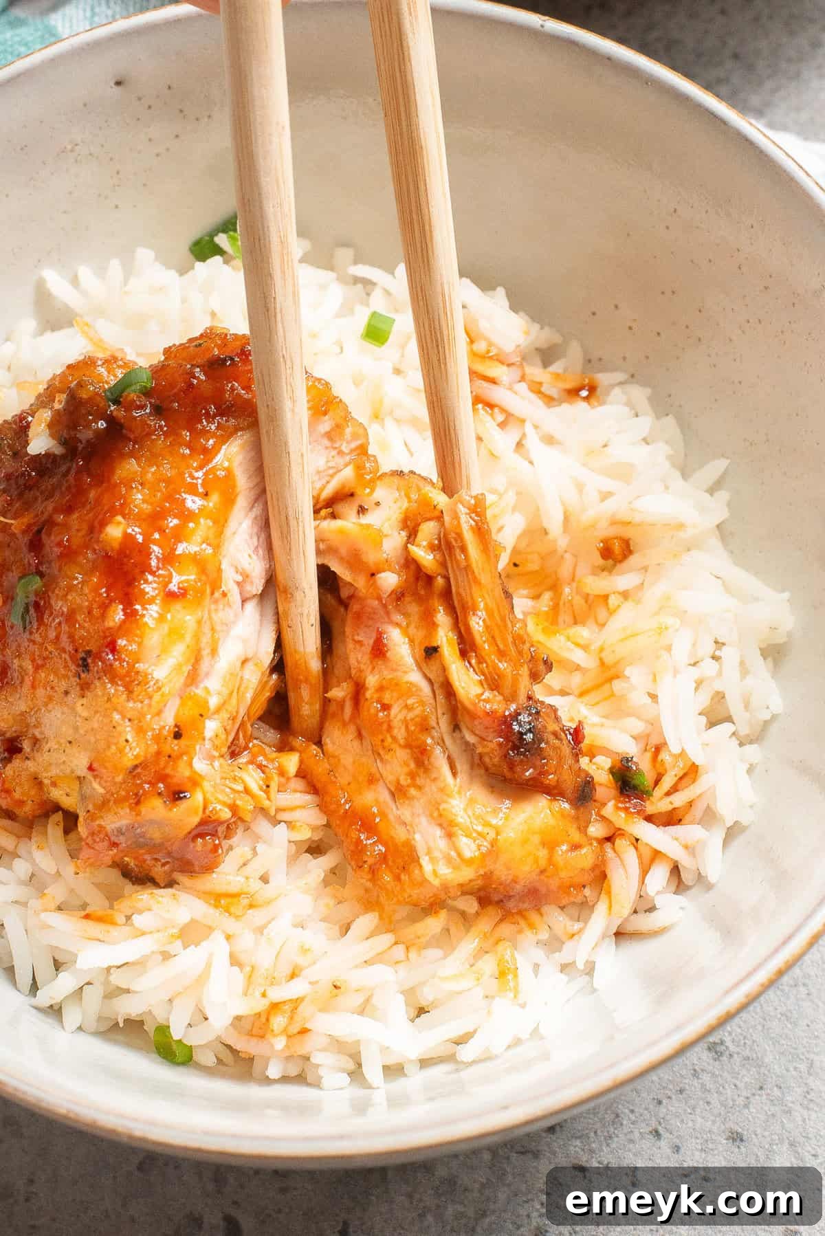 Honey Ginger Chicken served with chopsticks in a bowl, garnished with sesame seeds.