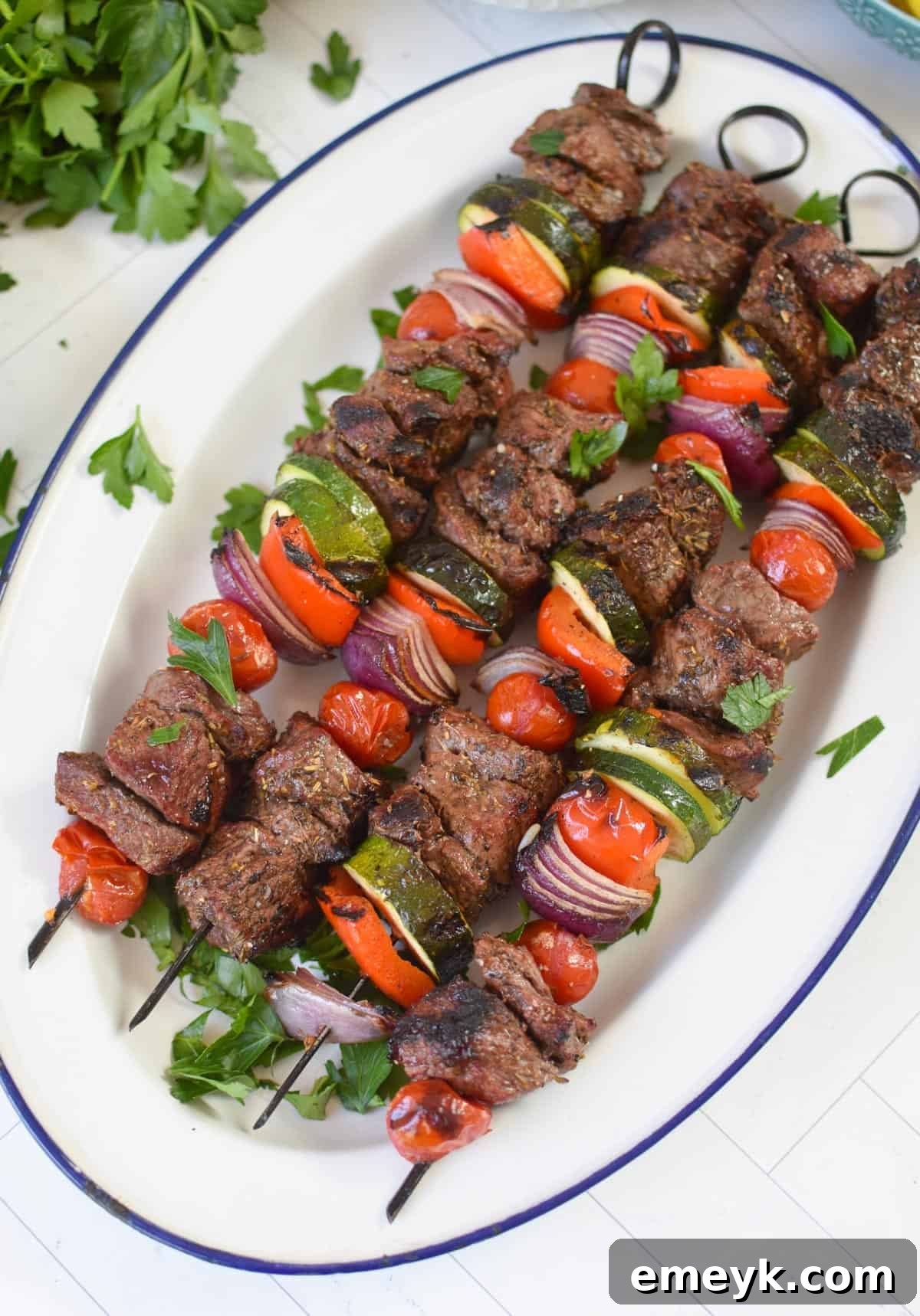 Tender Beef Souvlaki skewers artfully arranged on a pristine white platter, garnished with fresh herbs.