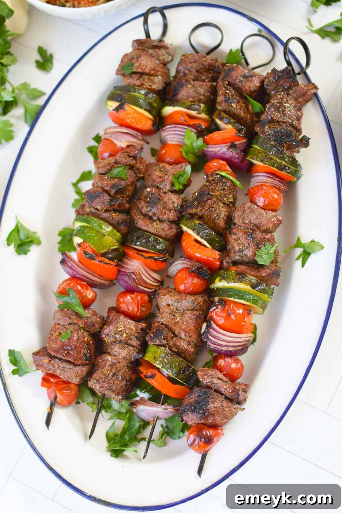 Plated Beef Souvlaki on a white platter, garnished with fresh herbs and ready for serving.