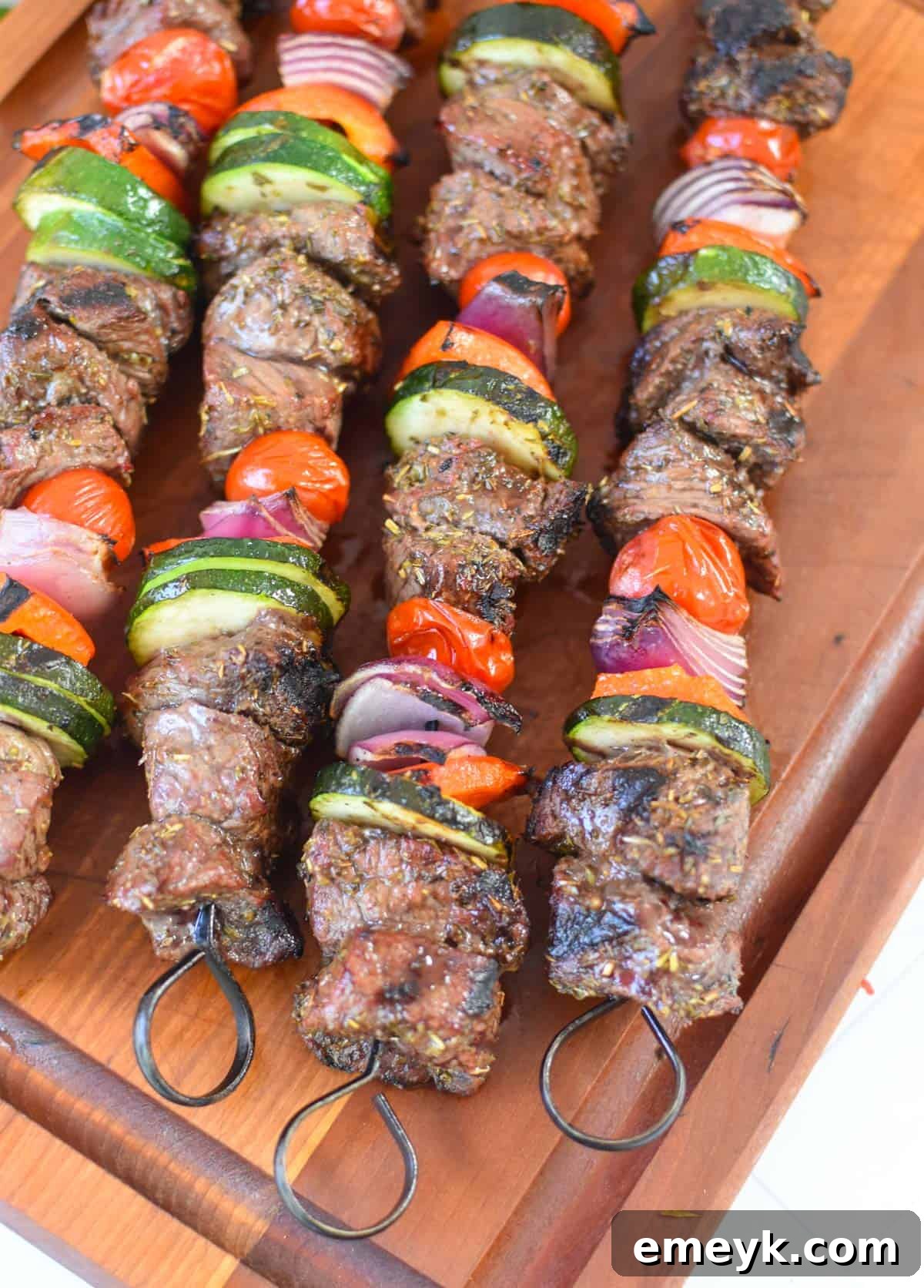 Cooked Beef Souvlaki skewers resting on a wooden cutting board, ready to be carved or served.