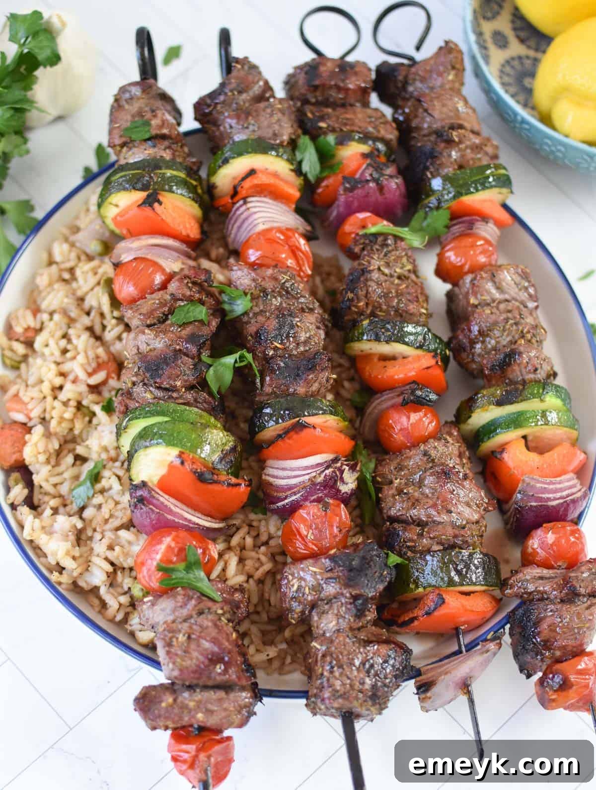 Beef Souvlaki skewers resting on a bed of fluffy white rice in a bowl, ready to be served.