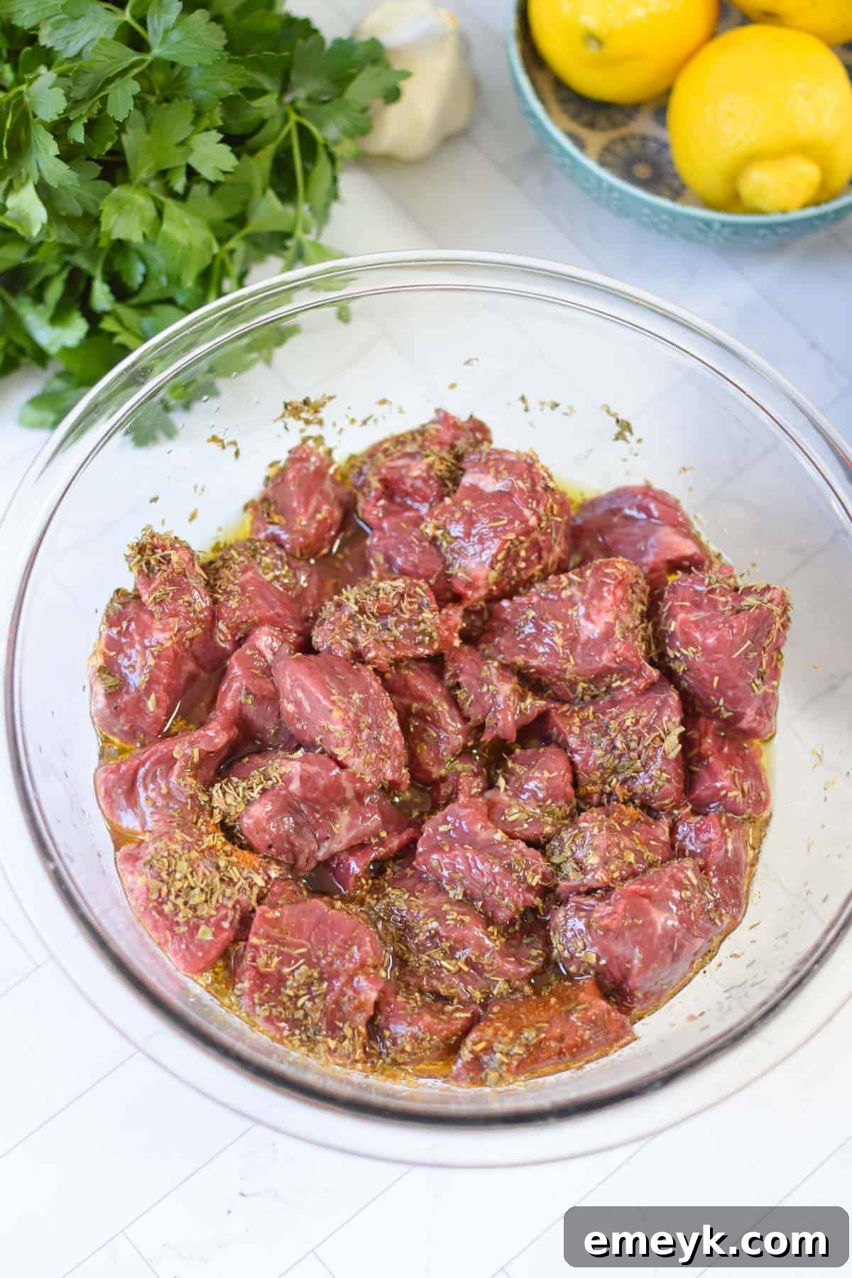 Cubed beef soaking in a bowl with a rich Greek marinade, ready for grilling.