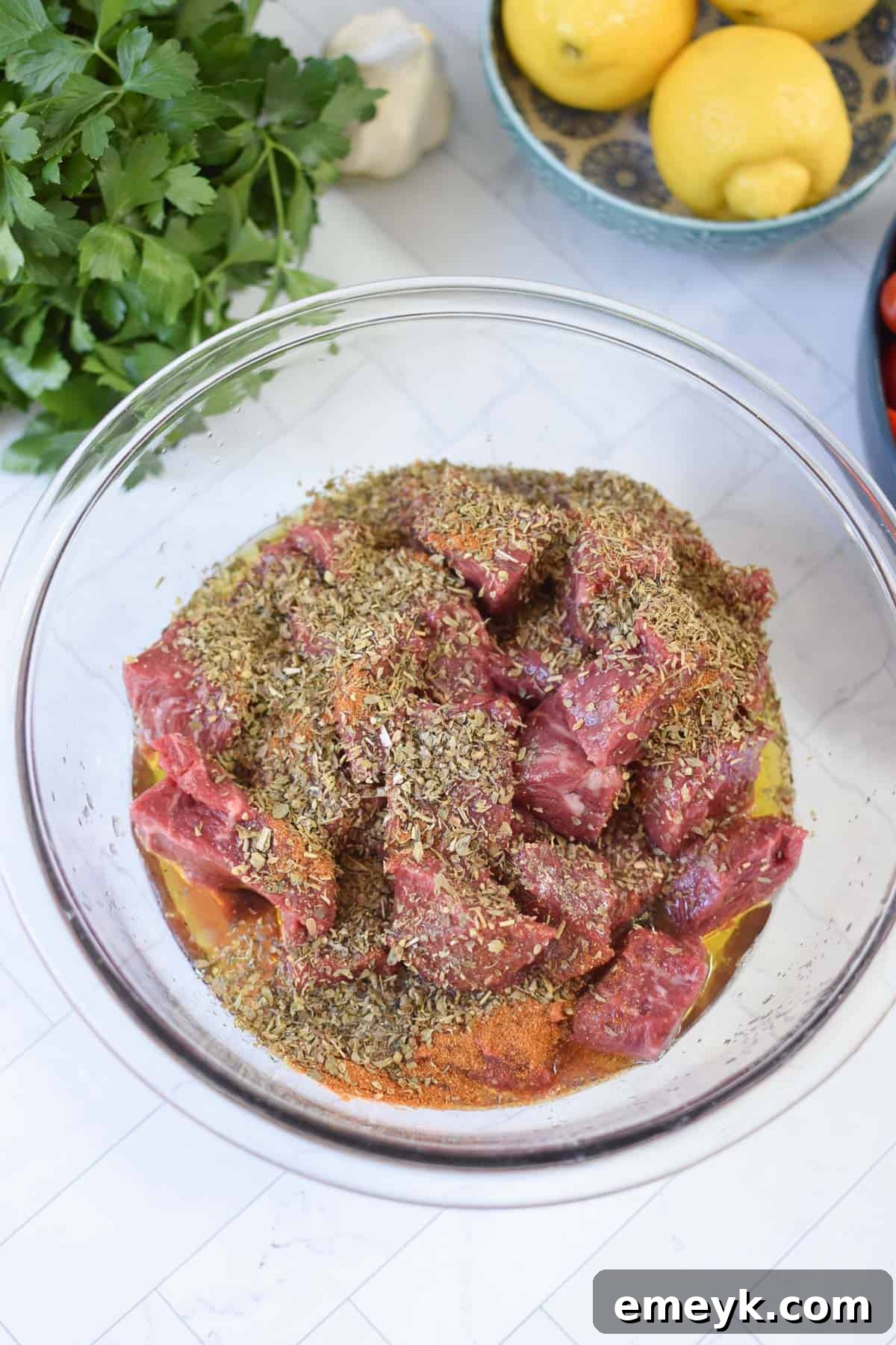 Cubed beef soaking in a bowl of vibrant Greek marinade, absorbing the rich flavors.