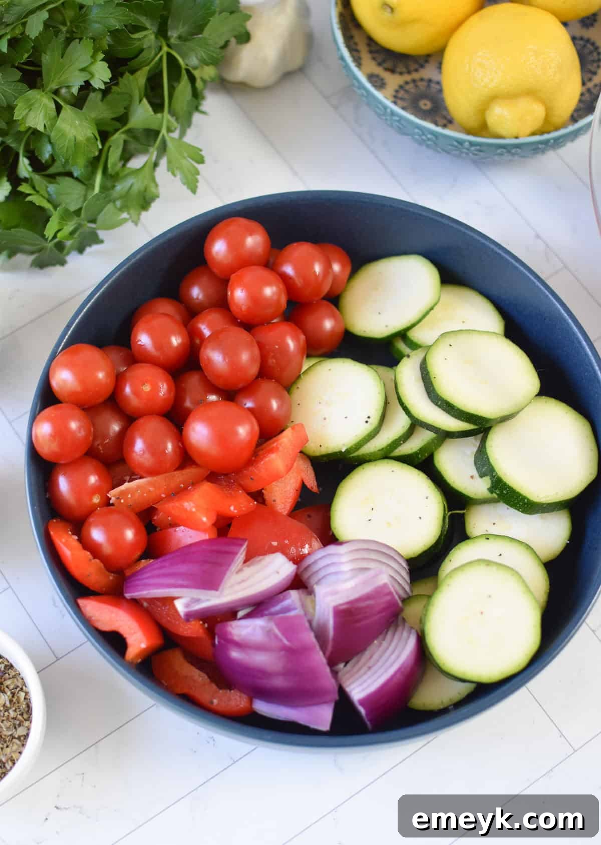 Mixed vegetables soaking in a bowl with Greek marinade, preparing for skewering.