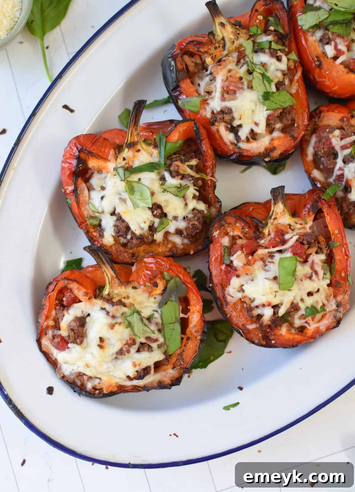 A single grilled stuffed pepper half garnished with fresh parsley on a white plate.