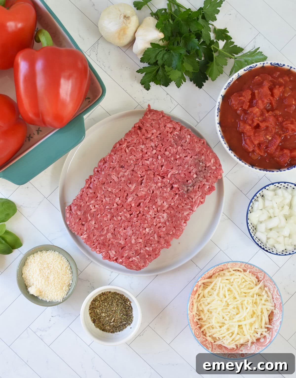A flat lay of fresh ingredients for Grilled Stuffed Peppers, including bell peppers, ground beef, rice, cheese, and tomatoes.