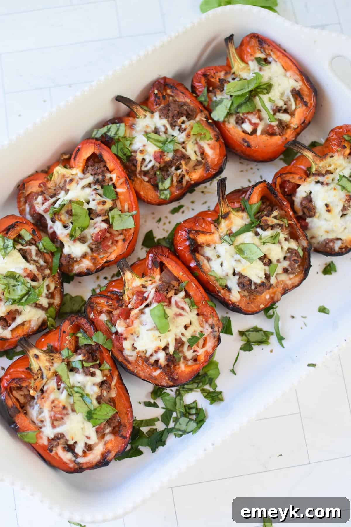 Close-up of a grilled stuffed pepper half with melted cheese and herbs.