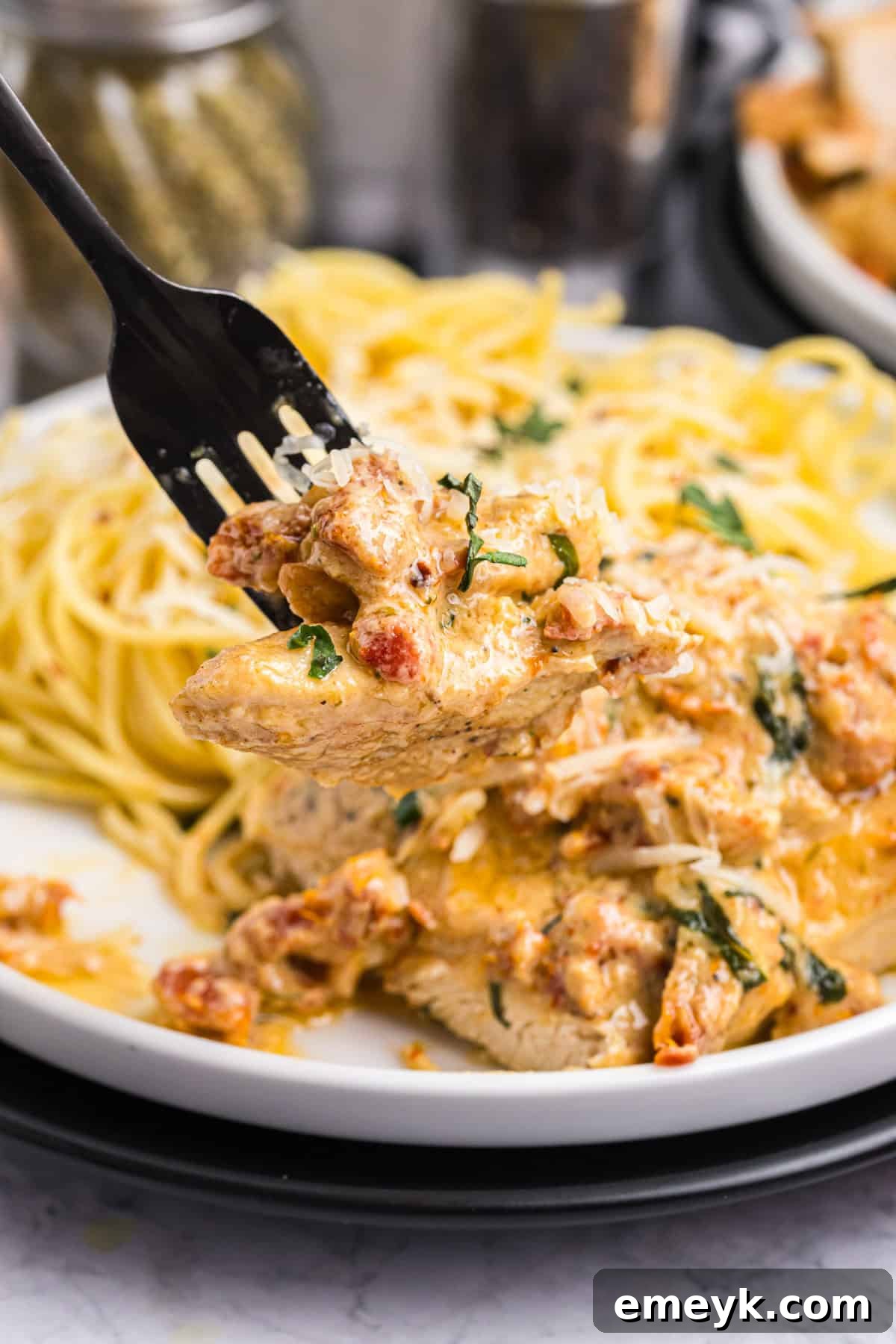 A close-up of Marry Me Chicken in a skillet, ready to be served, with a fork piercing a piece of chicken.