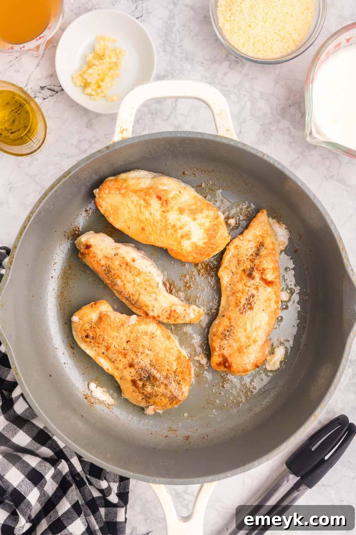 Chicken pieces sizzling and browning in a hot skillet with olive oil.