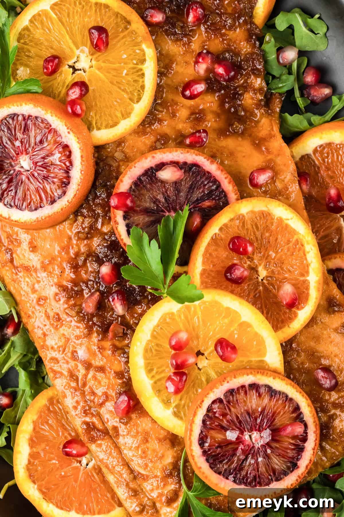 Exquisitely baked Orange Glazed Salmon garnished with fresh orange slices and vibrant pomegranate seeds, ready to serve.