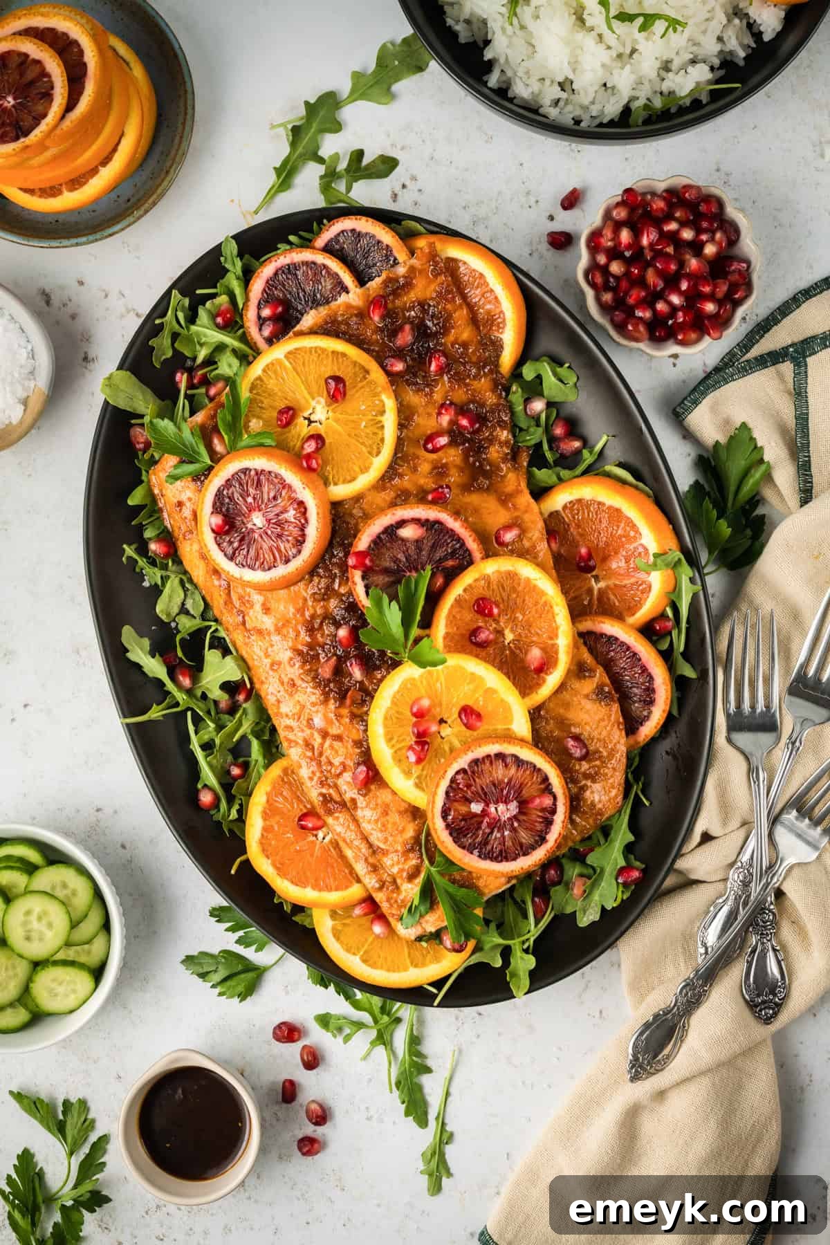Cooked Orange Glazed Salmon, beautifully presented on a black plate with a sprinkle of fresh pomegranate seeds, showcasing its rich color and inviting texture.