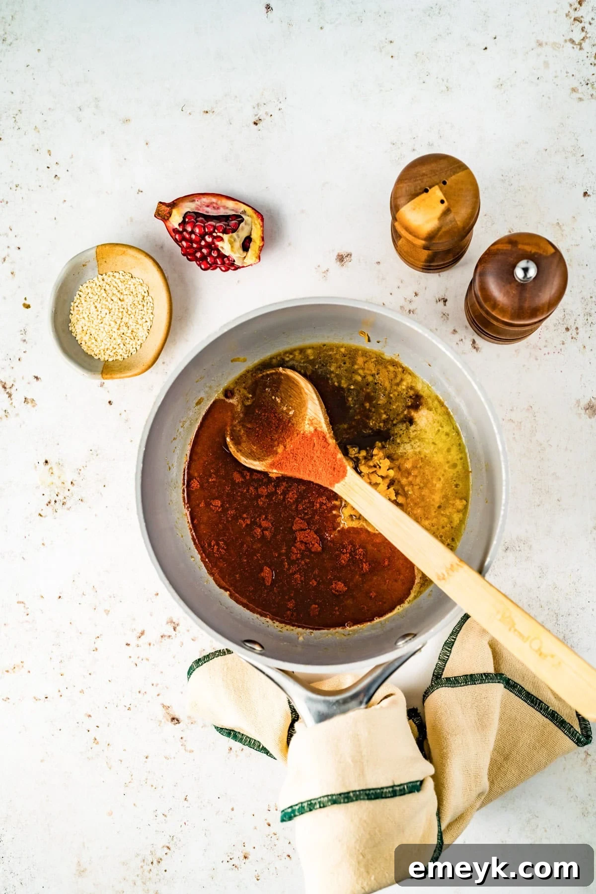 Ingredients for the orange glaze simmering in a saucepan on the stove, showing its developing rich color and texture.
