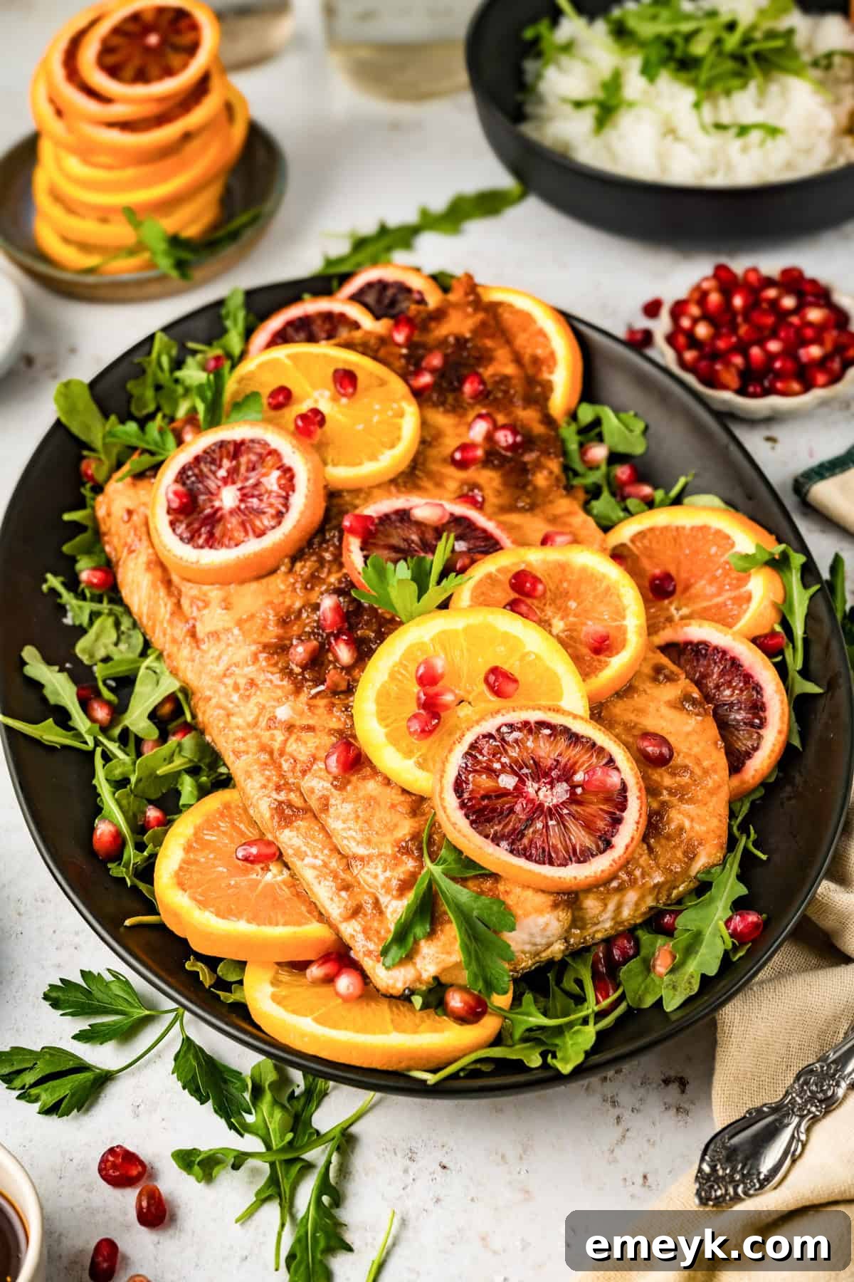 A perfectly cooked Orange Glazed Salmon fillet, garnished with fresh pomegranate arils and parsley, presented on a plate.