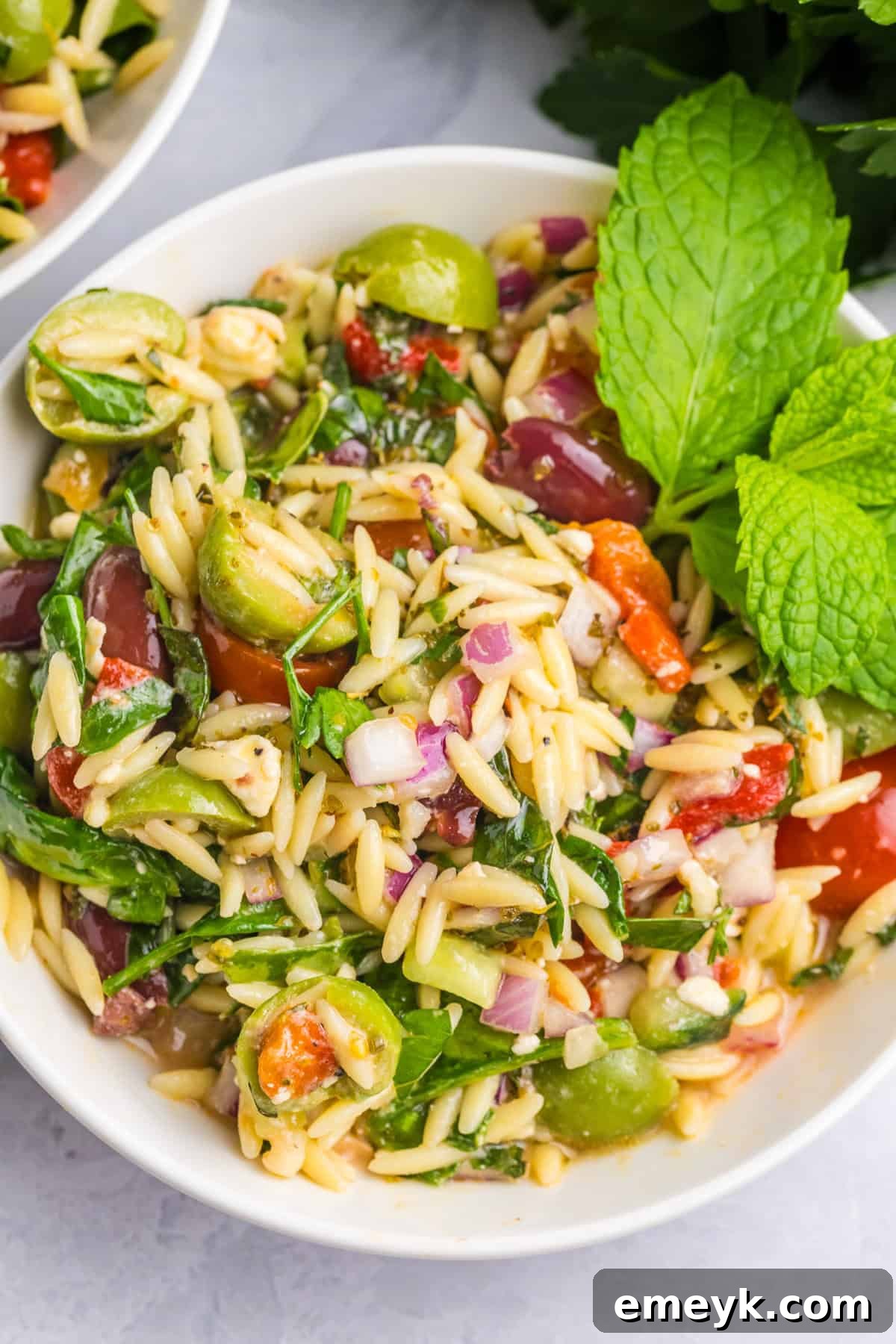 Mediterranean Pasta Salad in a white bowl, garnished with fresh herbs