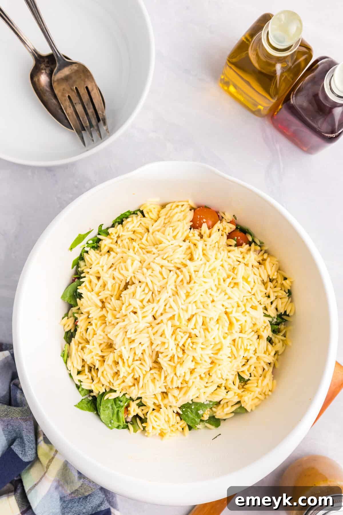 Cooled orzo pasta being added to the vegetable mix
