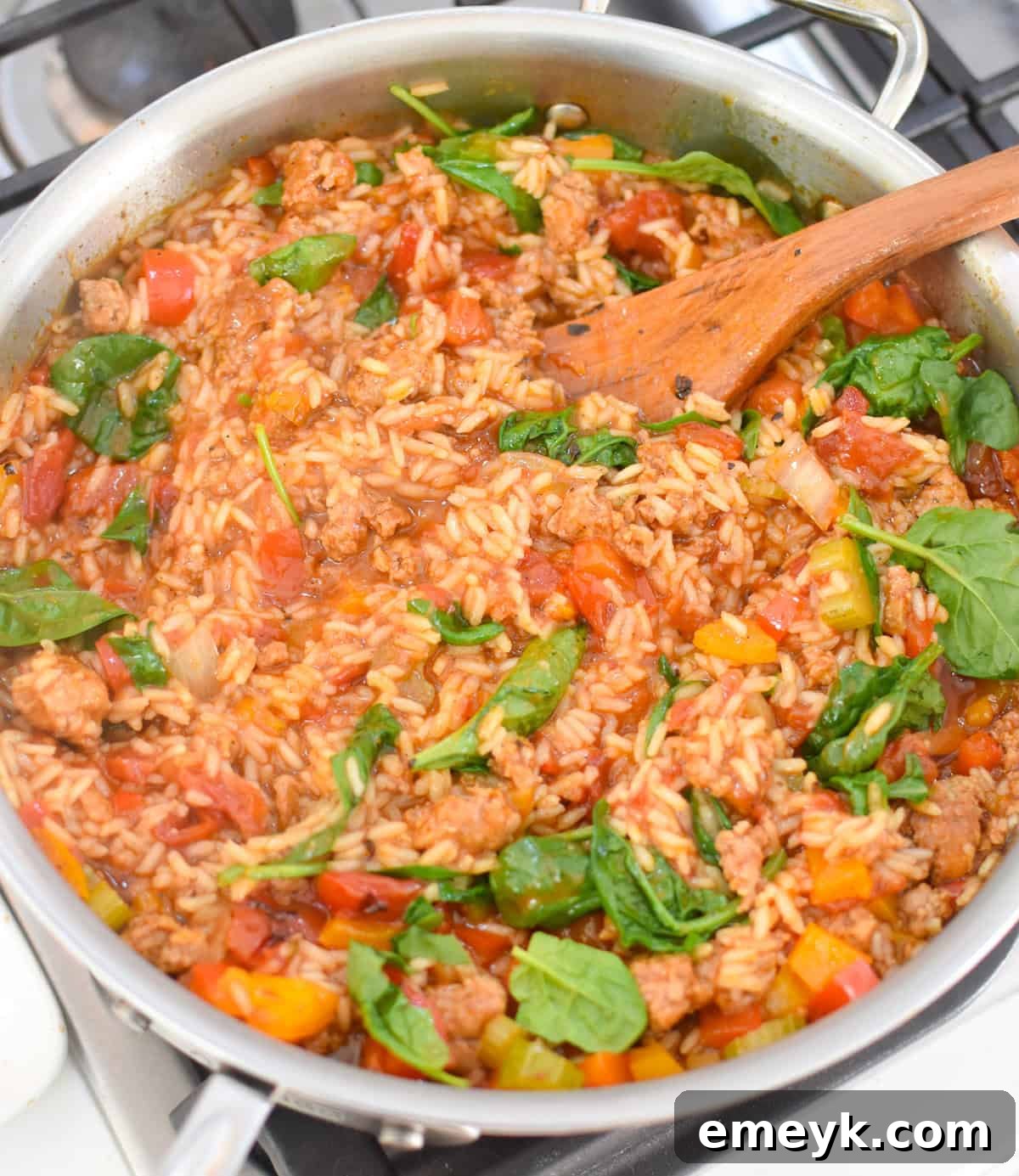 Spinach being stirred into the Creamy Cajun Sausage Rice Skillet