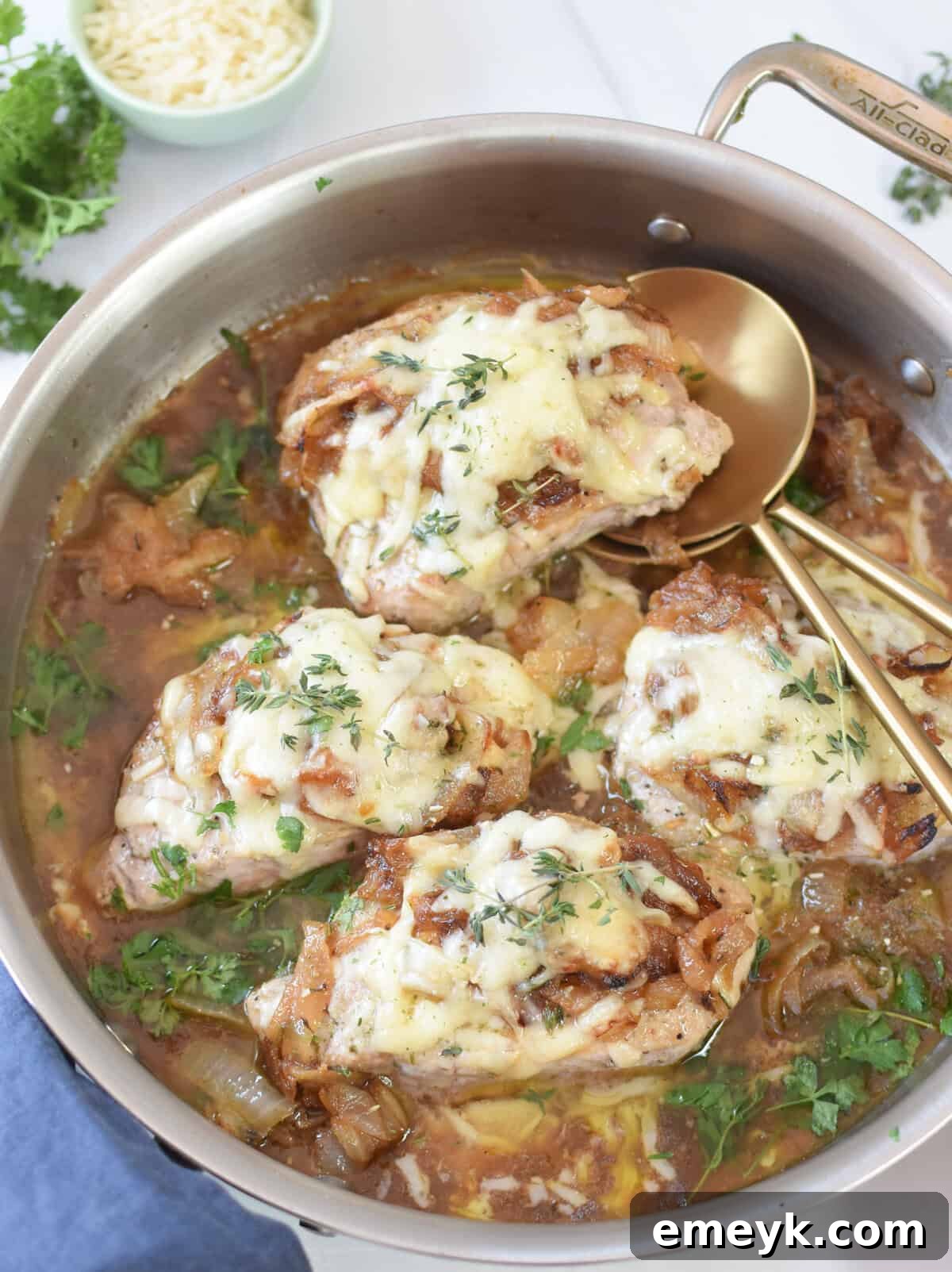 French Onion Smothered Pork Chops 5 Elegant French Onion Pork Chops presented with gold serving spoons, ready for dinner