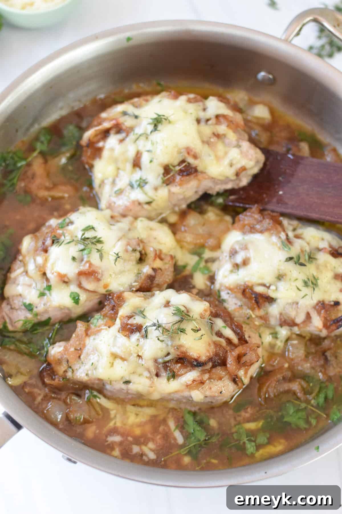 French Onion Smothered Pork Chops 9 French Onion Pork Chops in a cast iron skillet with a wooden spatula