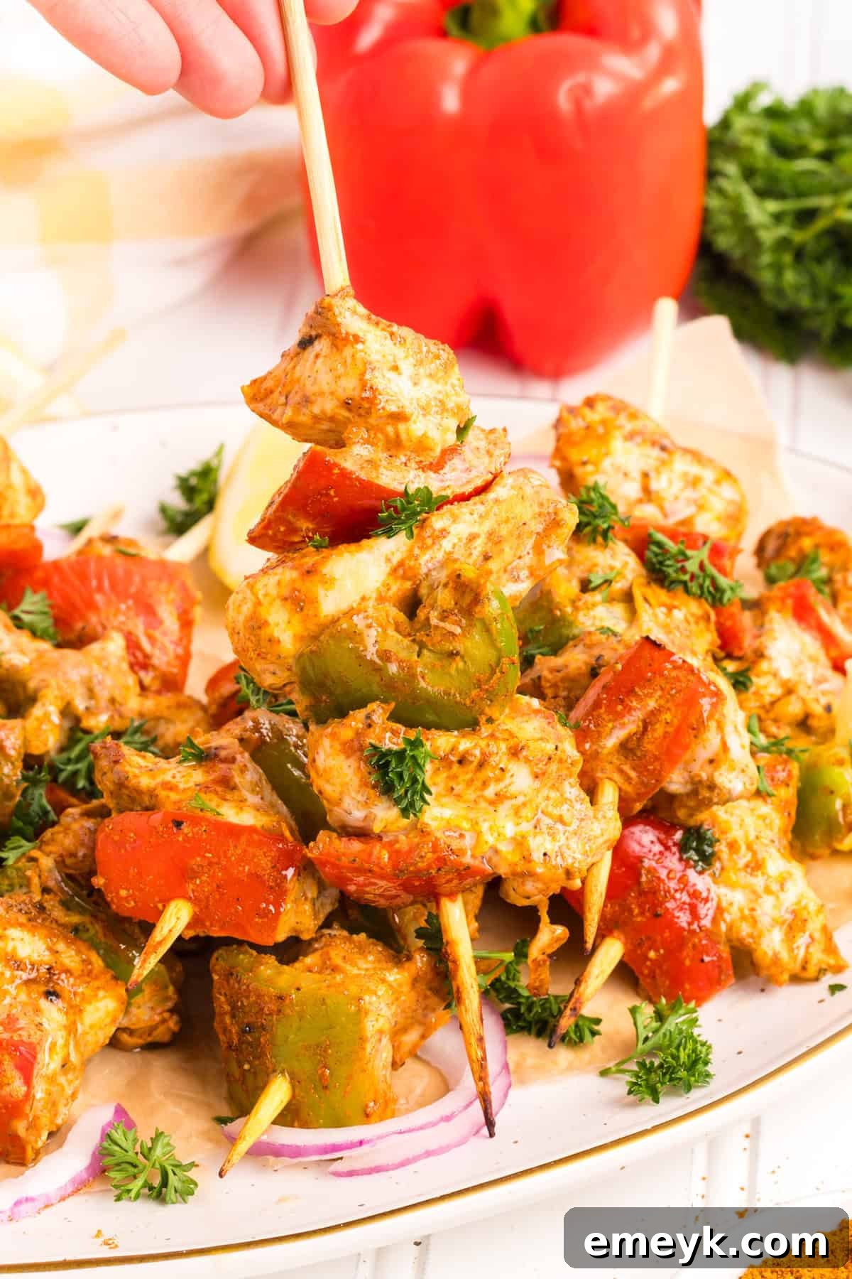 Cooked Chicken Tikka Kebabs served with colorful vegetables on a white background.