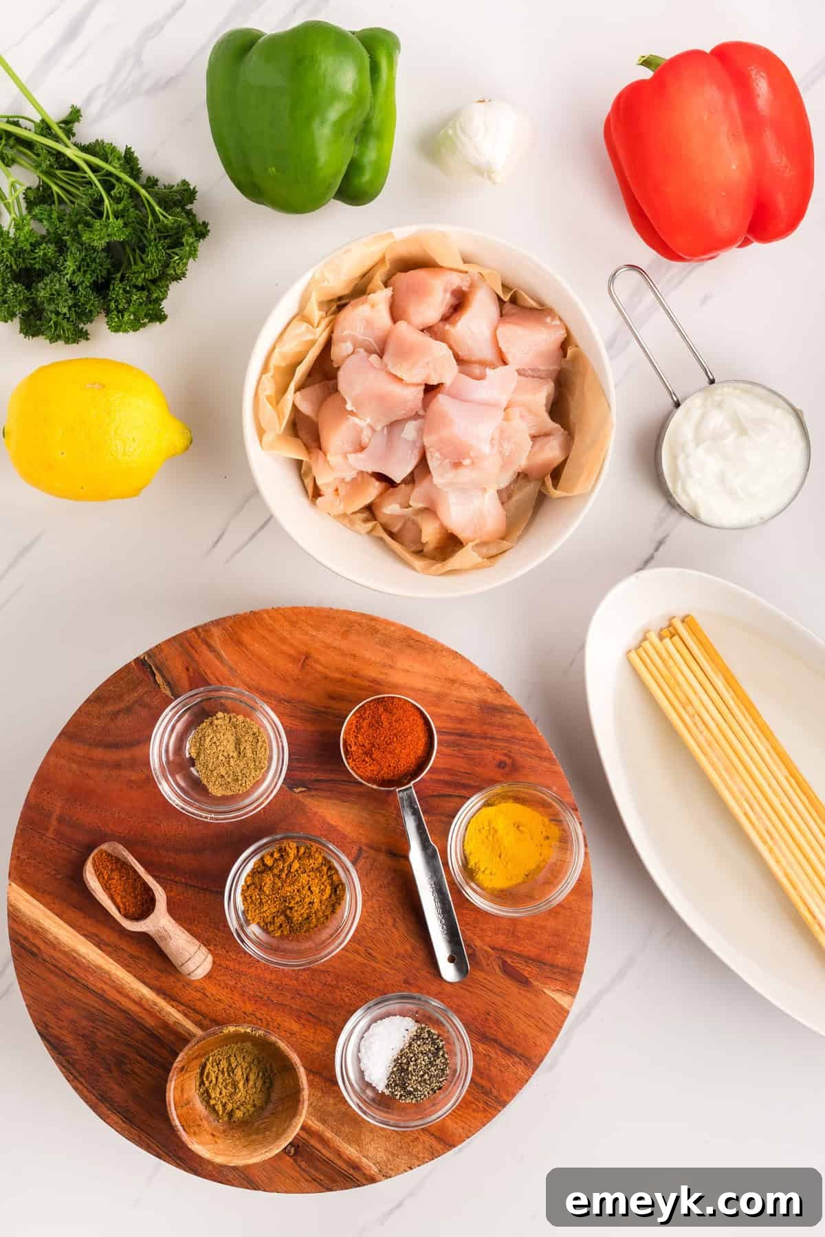 Fresh ingredients laid out for making Chicken Tikka Kebabs, including chicken, bell peppers, yogurt, and spices.