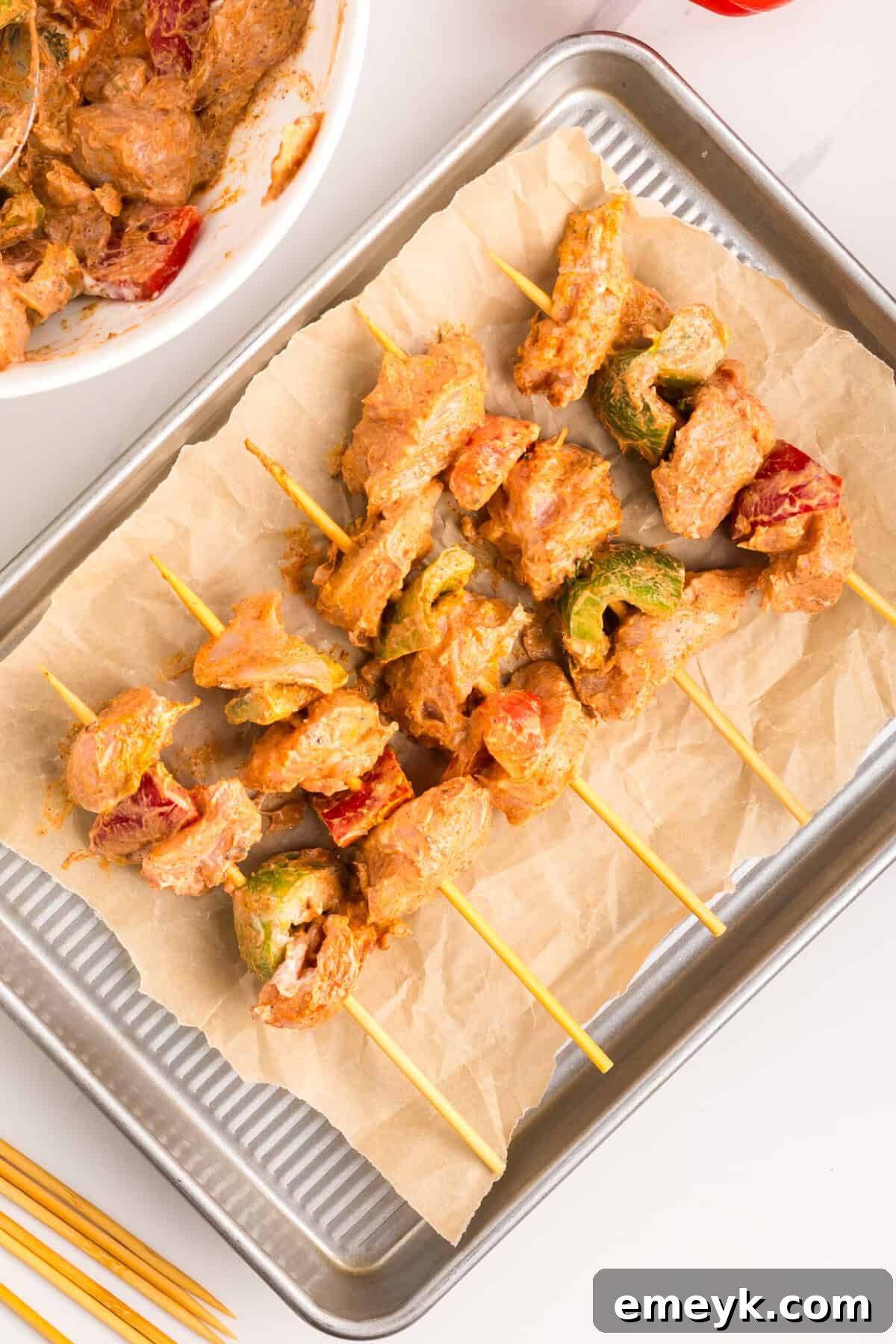 Assembled Chicken Tikka Kebabs with chicken and bell peppers threaded onto skewers, ready for the oven.