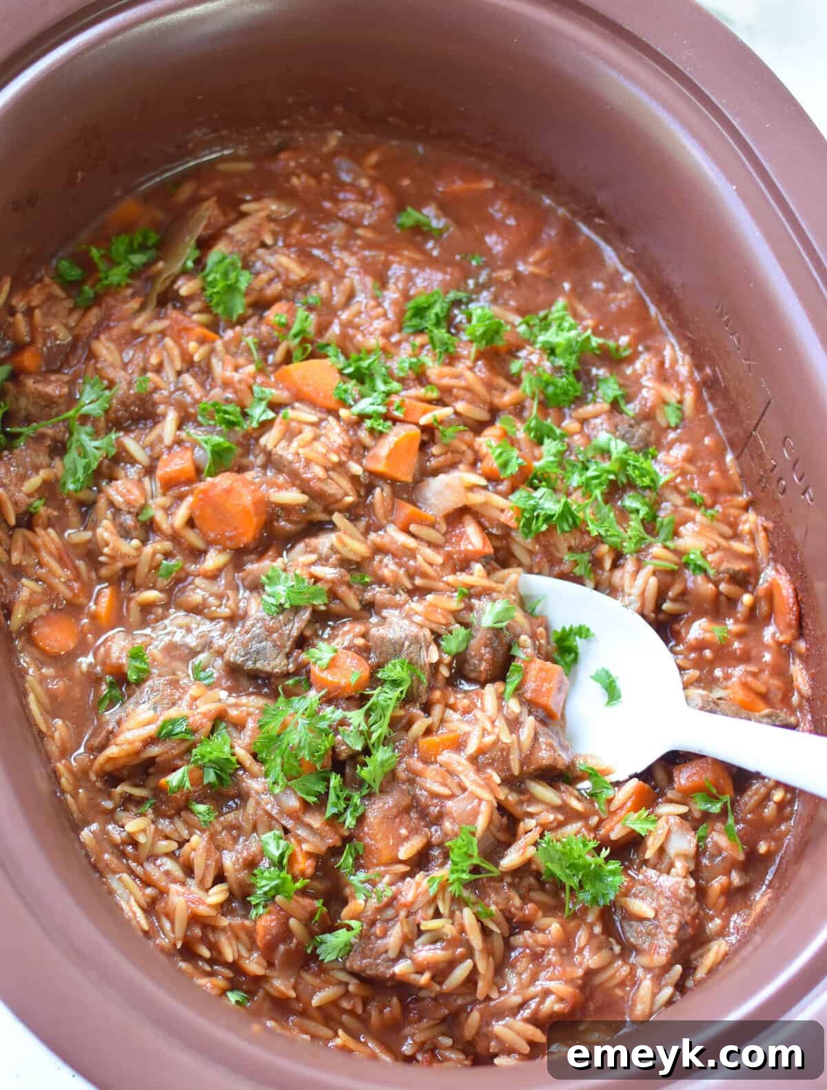 Greek Beef Stew with Orzo simmering in a slow cooker, showcasing the rich texture and color.