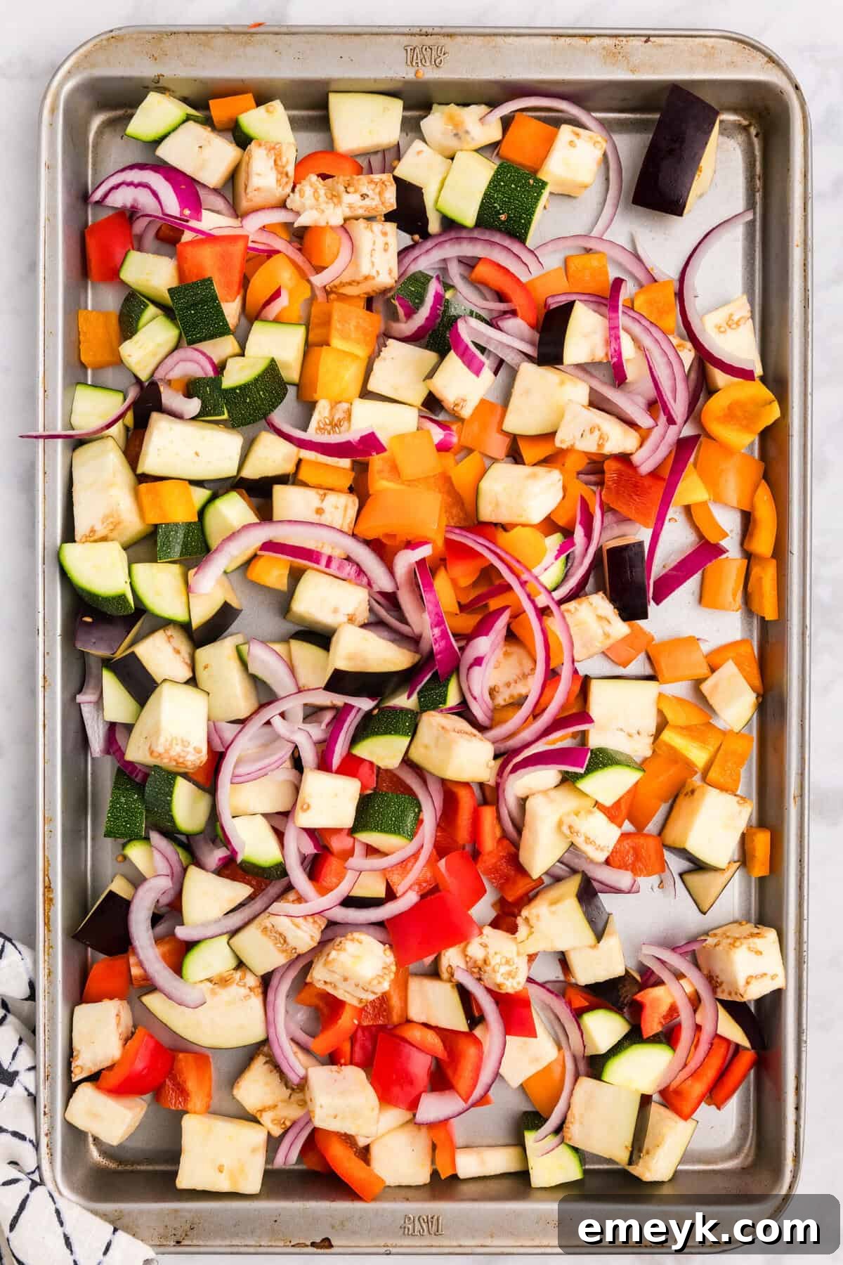 Mediterranean Harvest Roasted Pasta Bake 5 Chopped vegetables and minced garlic drizzled with olive oil on a baking sheet, ready for seasoning