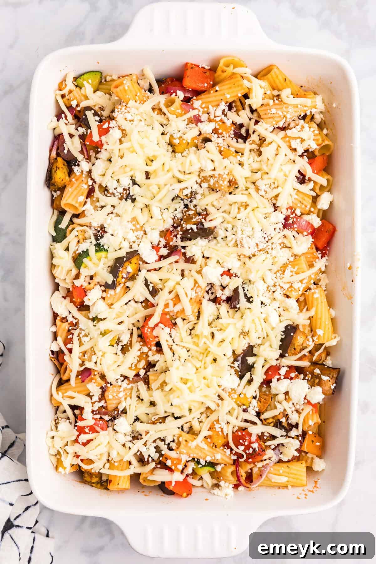 Mediterranean Harvest Roasted Pasta Bake 7 Mediterranean Roasted Vegetable Pasta Bake topped with feta and mozzarella cheese, ready to be baked
