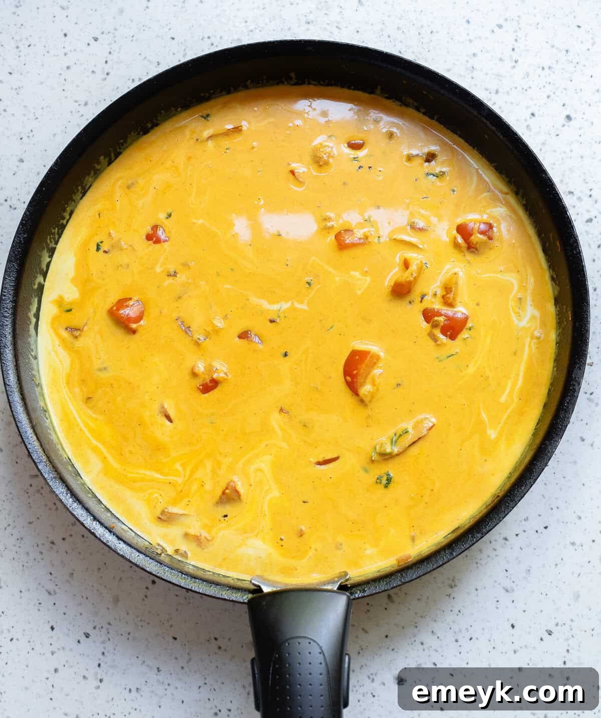 Coconut Fish Curry sauce simmering in a black skillet before fish is added