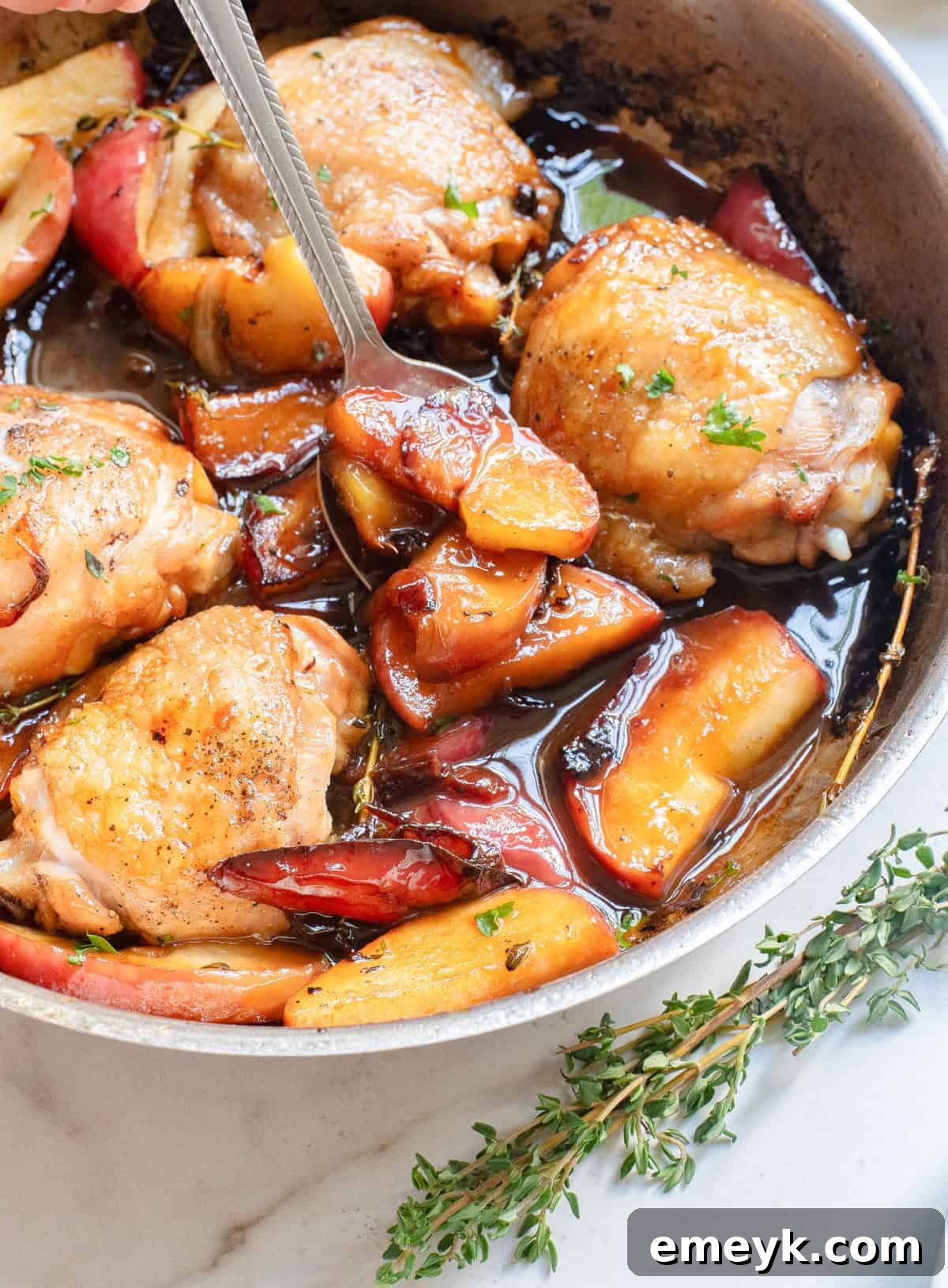 Skillet Apple Cider Chicken being served with a spoon, highlighting the saucy goodness.