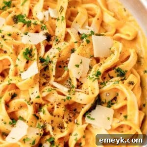 A vibrant bowl of creamy pumpkin pasta garnished with fresh sage leaves and a hint of grated cheese, capturing the essence of a perfect fall meal.