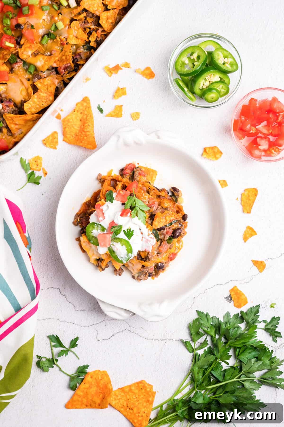 A slice of Doritos Taco Casserole on a plate with fresh toppings like avocado and cilantro.