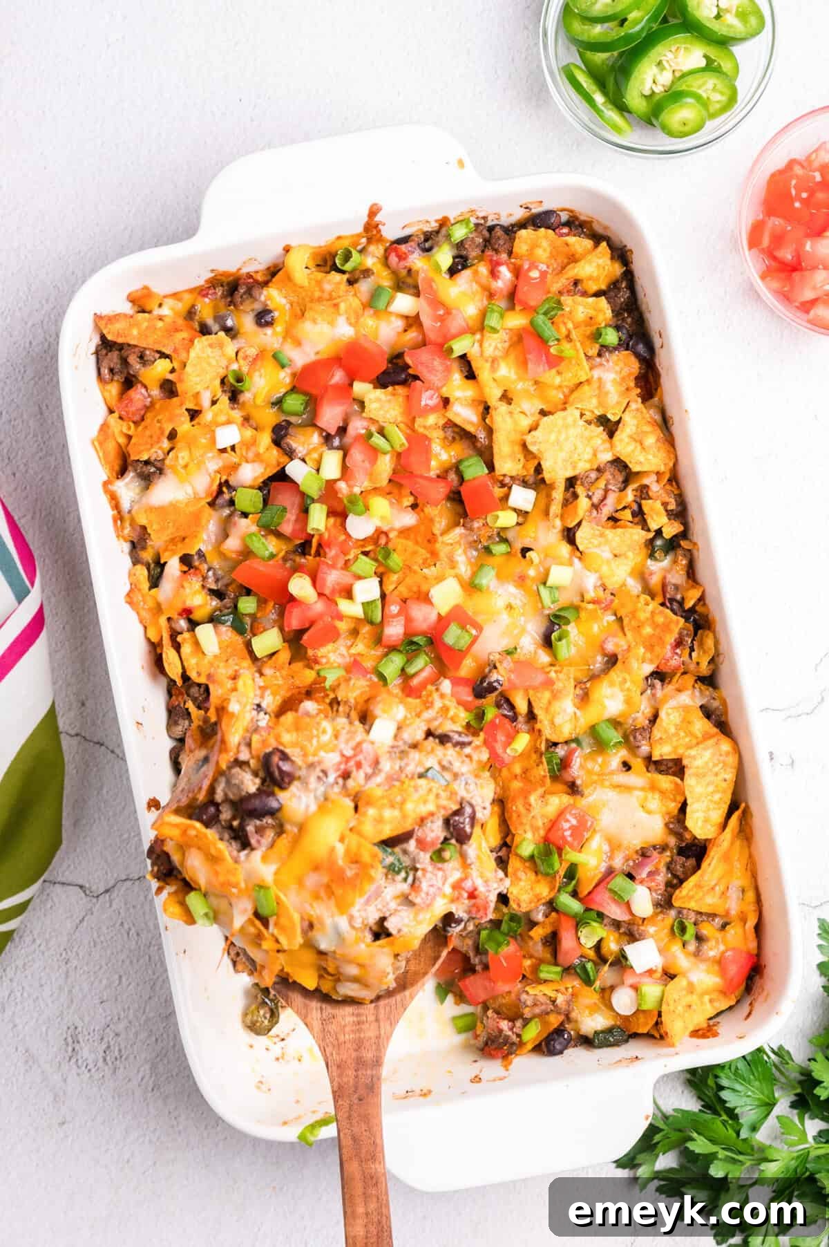 Doritos Taco Casserole baking in a white ceramic dish, showing a golden, bubbly cheese top.