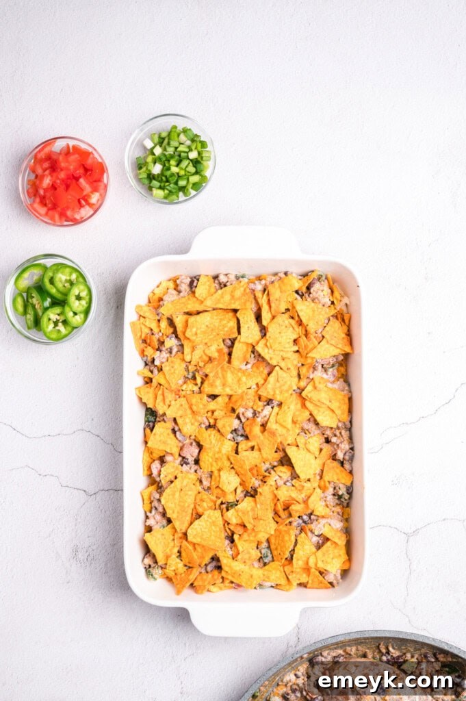 Doritos chips layered over the ground beef mixture in the baking dish, creating a crunchy texture.