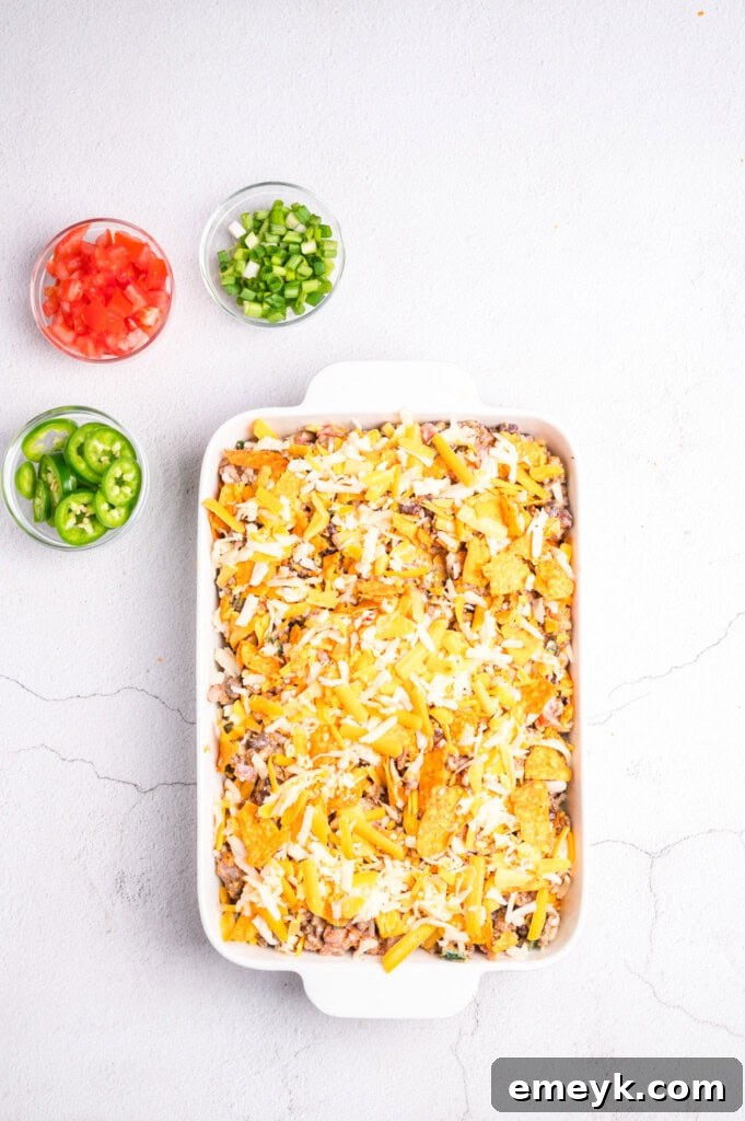 The Doritos Taco Casserole layered and ready for the oven, with cheese and chips on top.