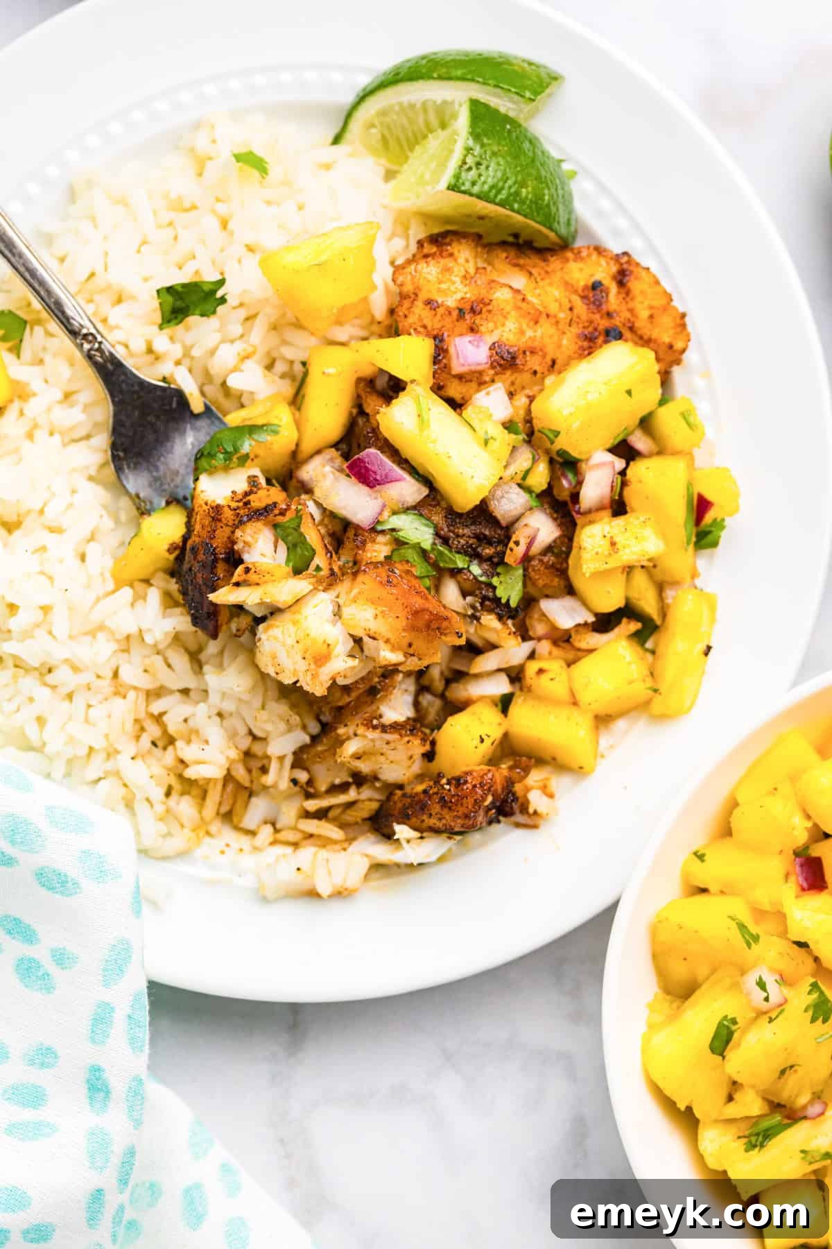 Effortless Blackened Cod 7 A fork taking a piece of Easy Blackened Cod served with pineapple salsa and rice