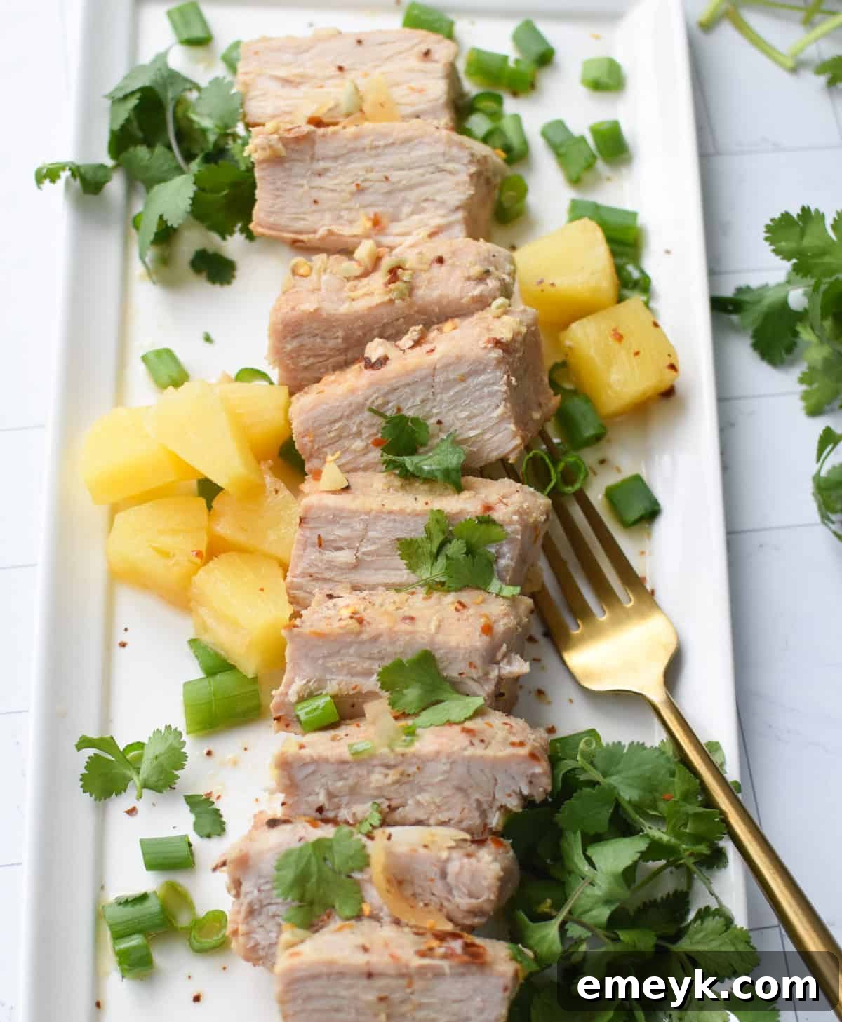 Slow Cooker Pineapple Pork Loin sliced on a platter with serving utensils, ready for the table.